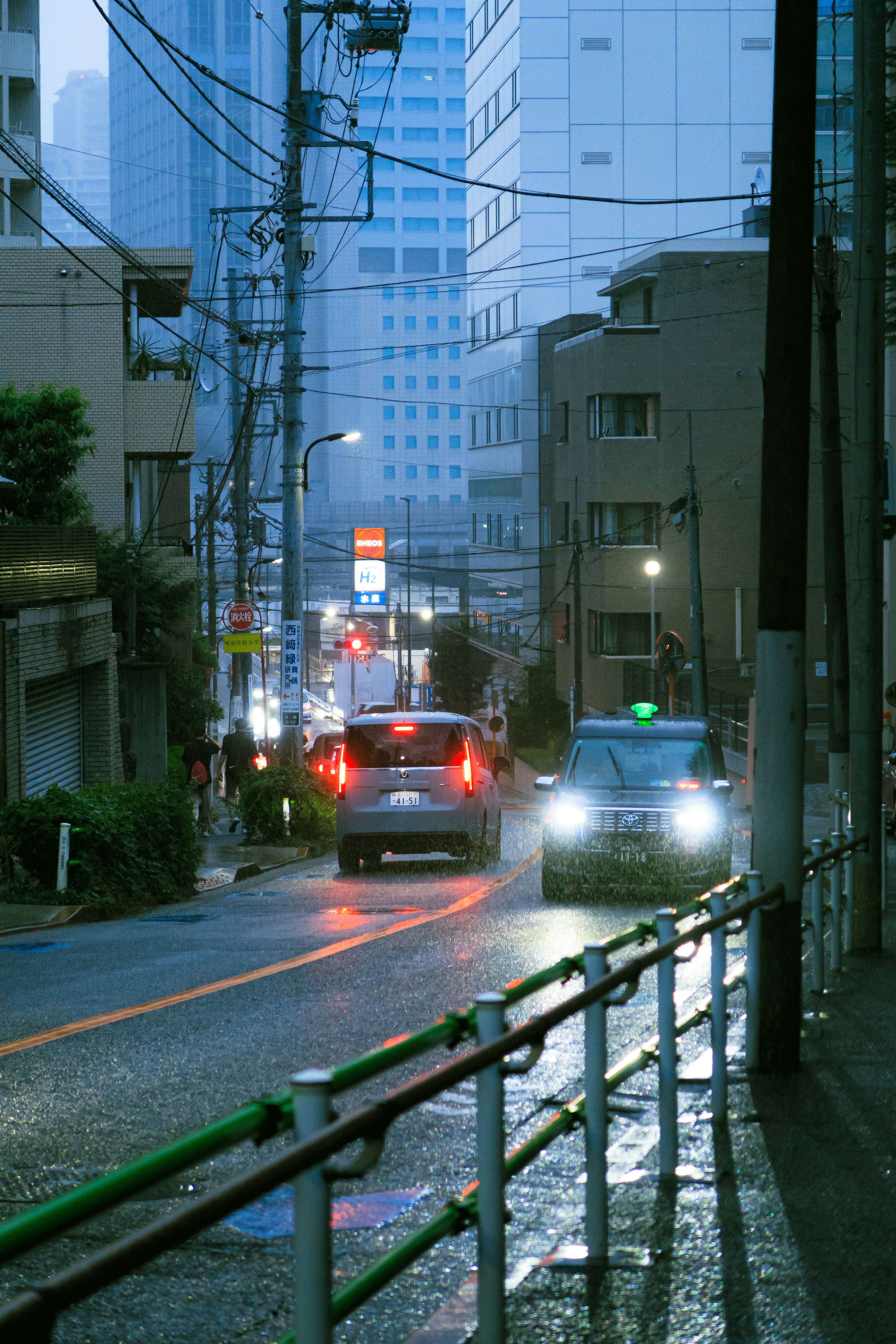 雨の桂坂を走る車と街灯のある路地