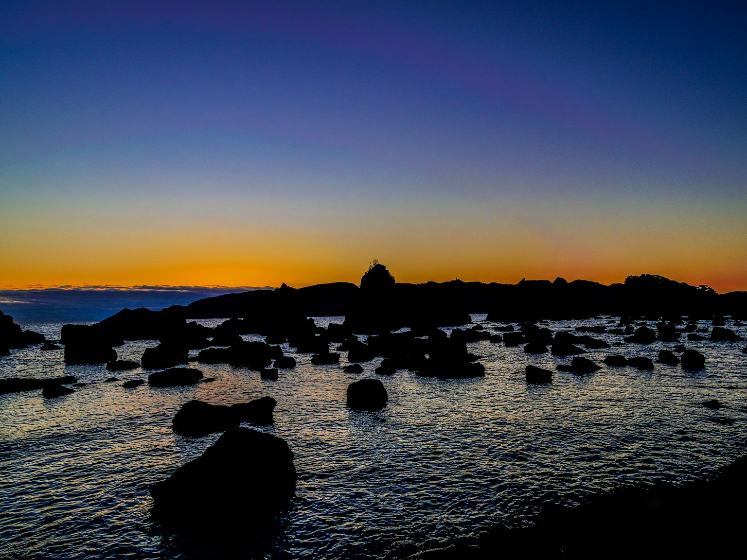 Schöne Küste bei Sonnenuntergang mit Felsen und ruhigem Wasser