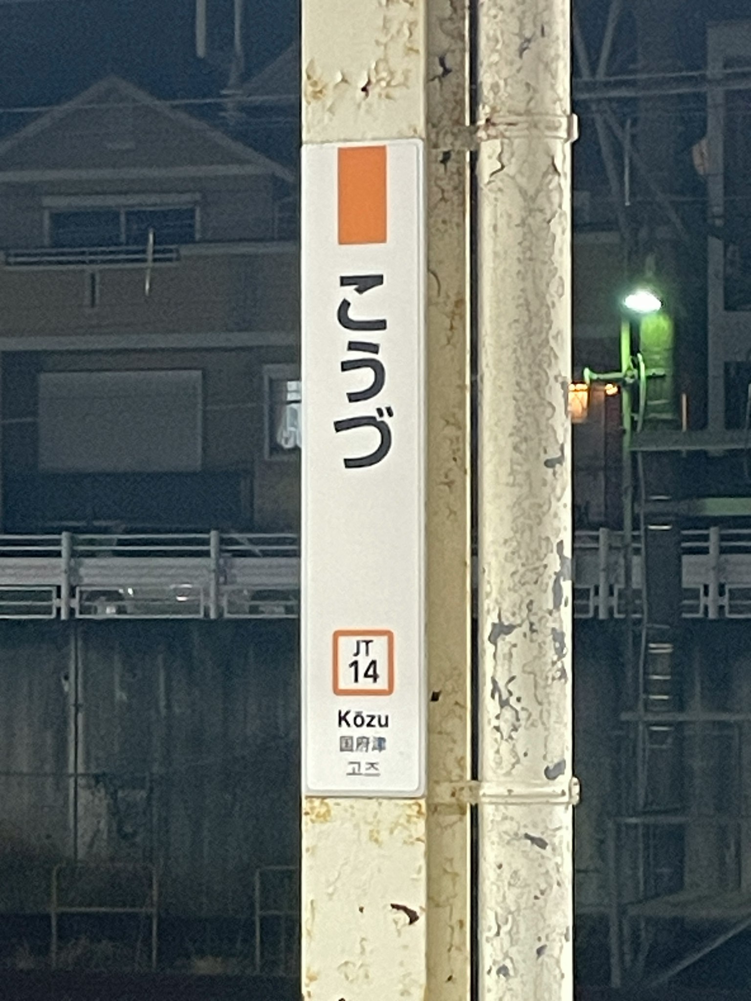 Hiragana-Schild und Stationsnummer nachts in einem Bahnhof sichtbar
