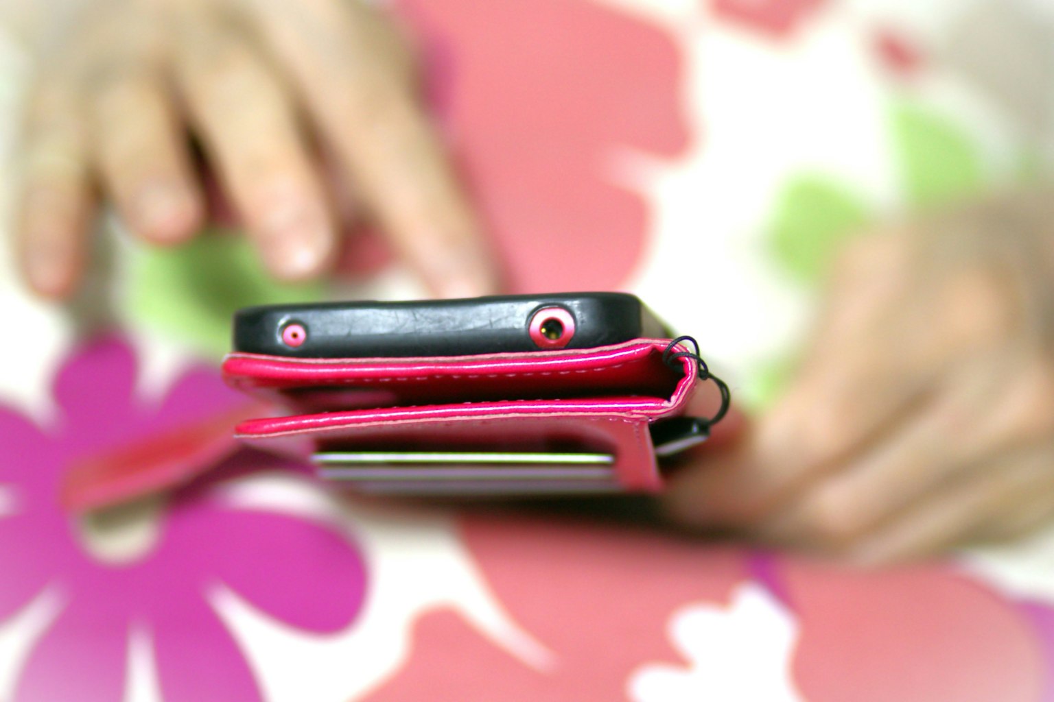 A smartphone in a pink case with hands visible