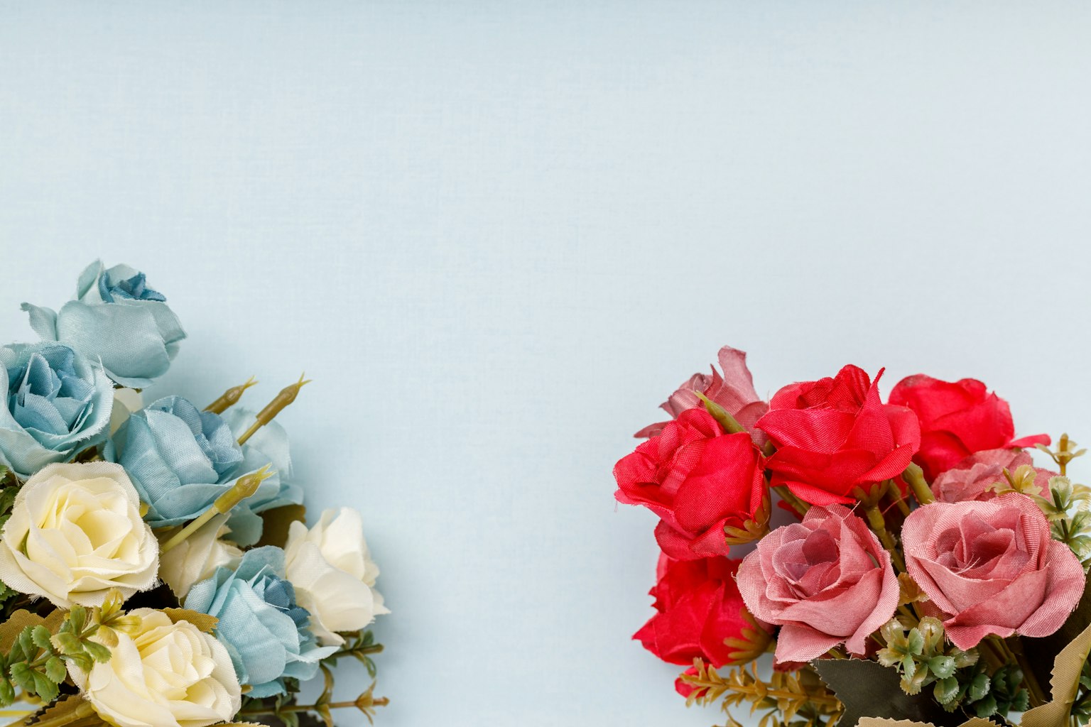 Bündel aus blauen und roten Rosen symmetrisch auf einem hellblauen Hintergrund angeordnet