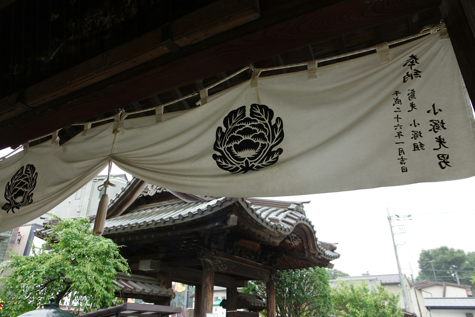 Traditional Japanese entrance featuring a white noren with black floral patterns and text