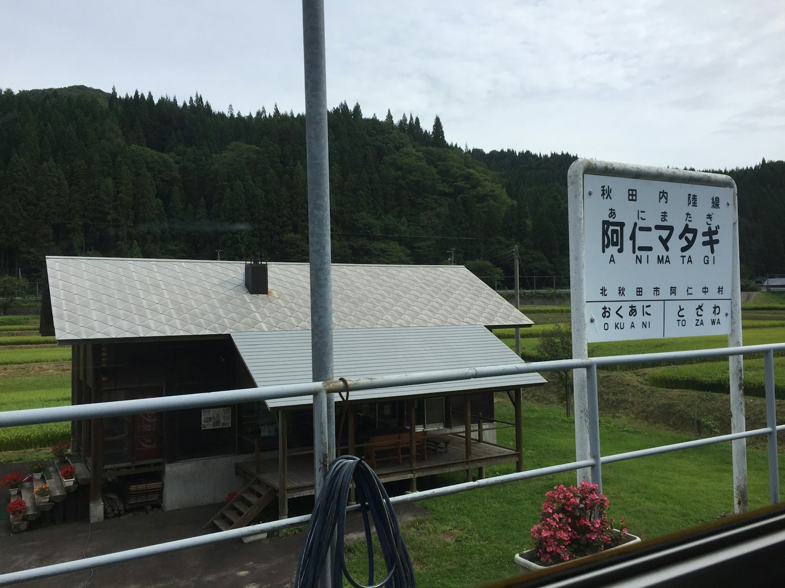 Schild der Ani Matagi Station mit umliegender ländlicher Landschaft