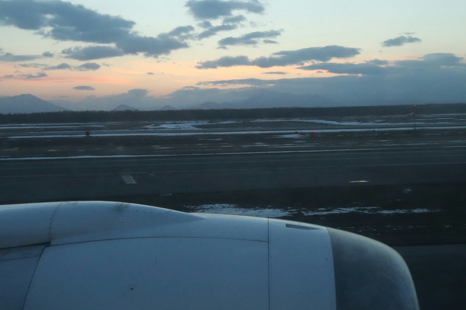 Vista dell'ala di un aereo e della pista al tramonto