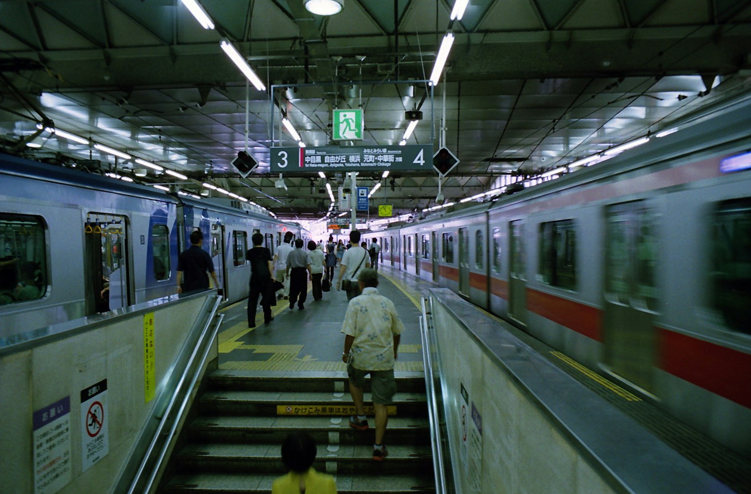 Persone che si dirigono verso il tornello con treni sullo sfondo