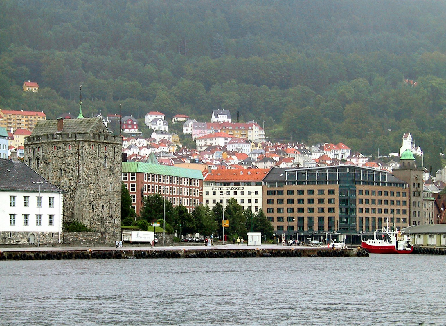 Historic stone tower alongside modern buildings in a waterfront cityscape