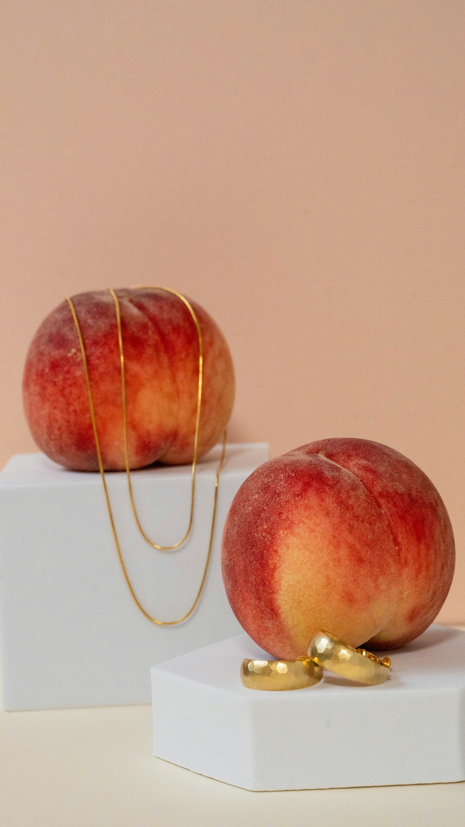 Stylish still life featuring red apples adorned with gold necklaces and rings