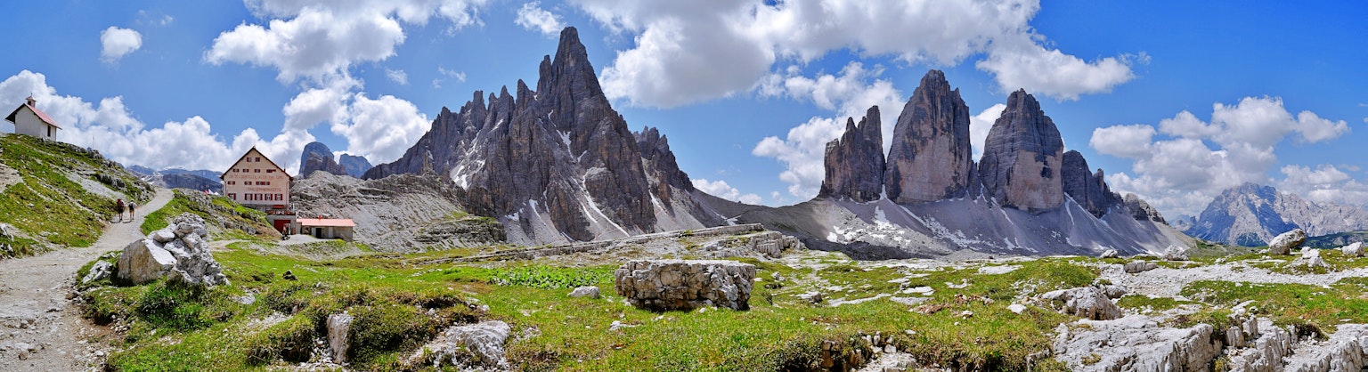 Malersicher Blick auf majestätische Berge unter einem blauen Himmel üppige grüne Wiese mit verstreuten Steinen