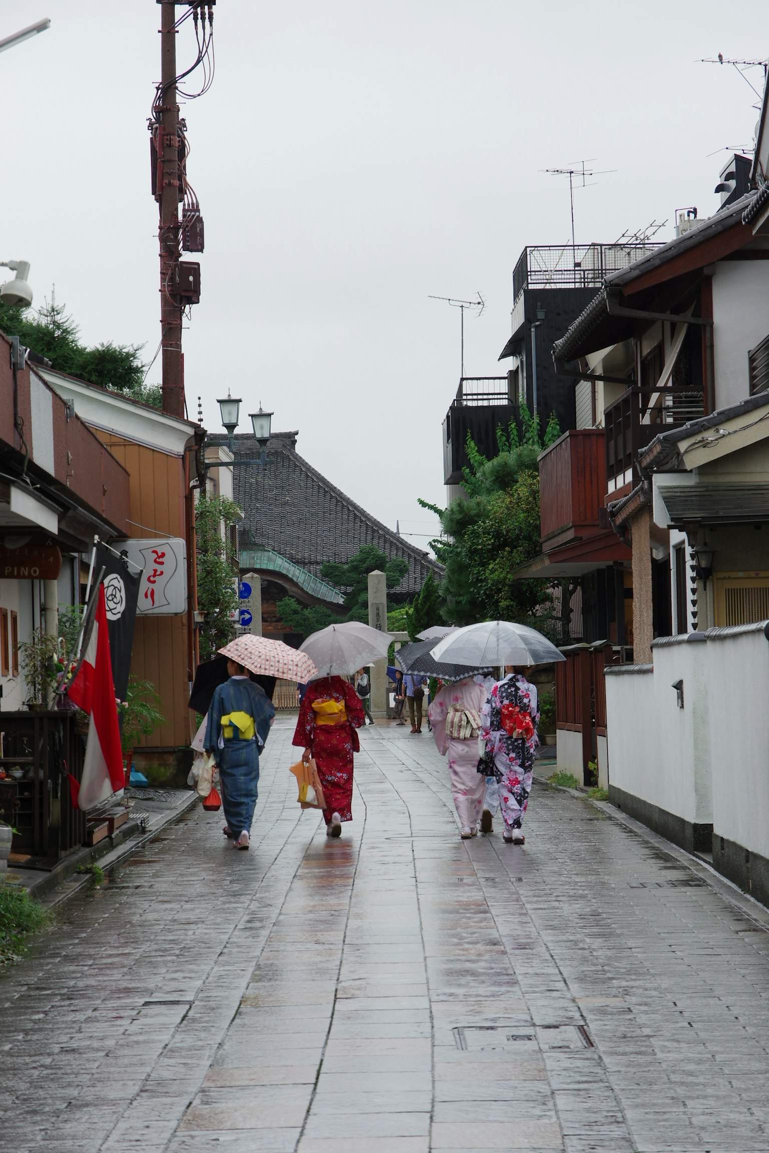 Menschen im Kimono, die im Regen unter Regenschirmen gehen