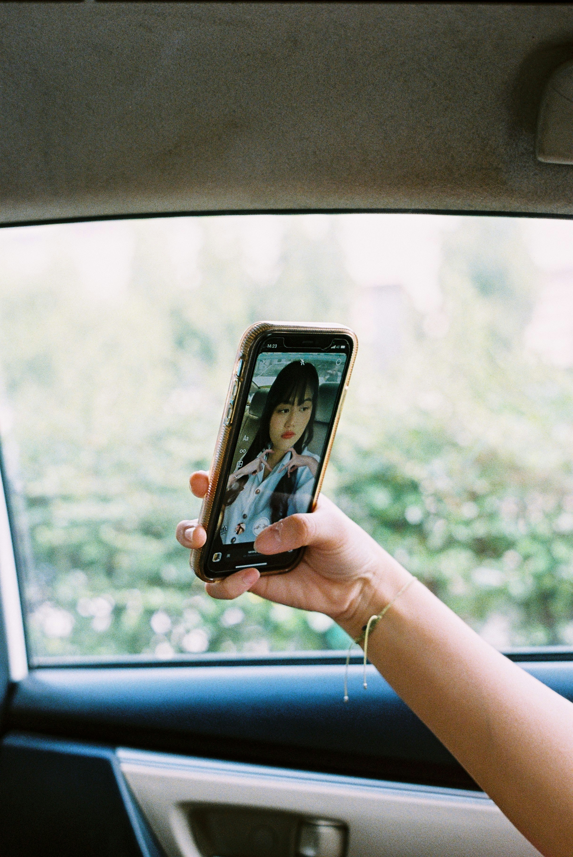 車内でスマホを手に持つ人物と画面の人物