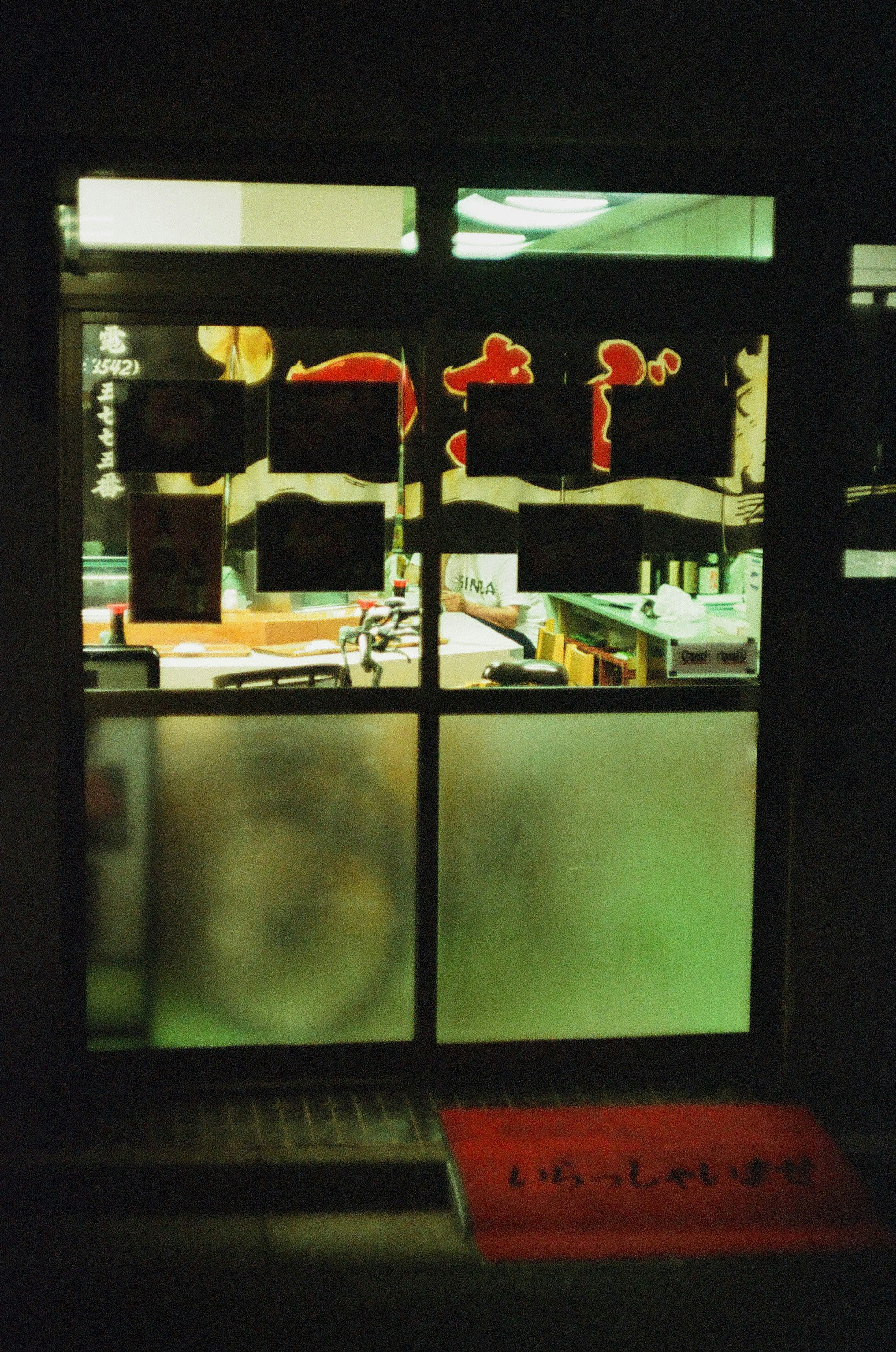夜の窓に並ぶカラフルな店内ディスプレイの画像