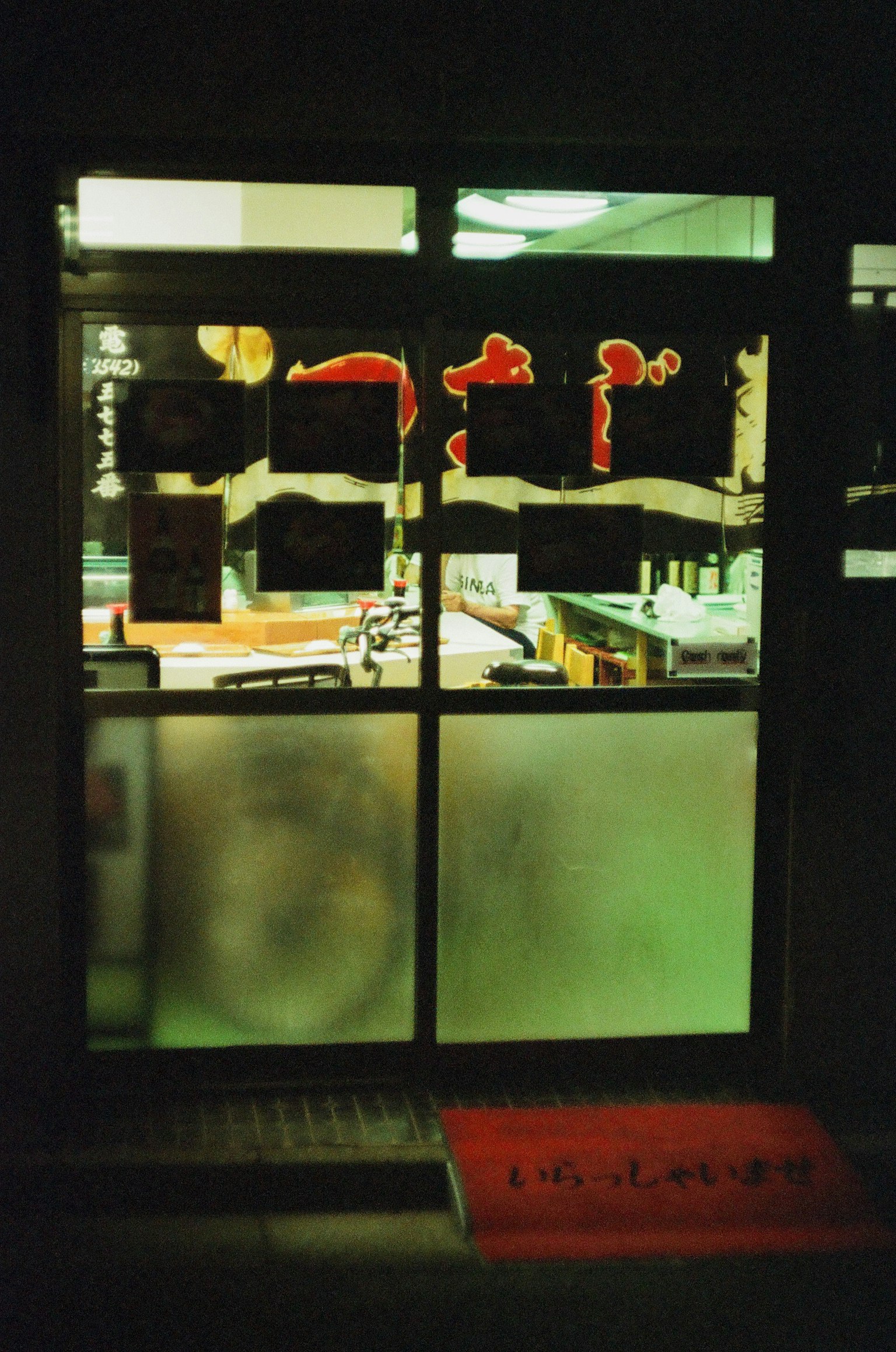 餐厅窗户，带有红色标志和磨砂玻璃，背景昏暗