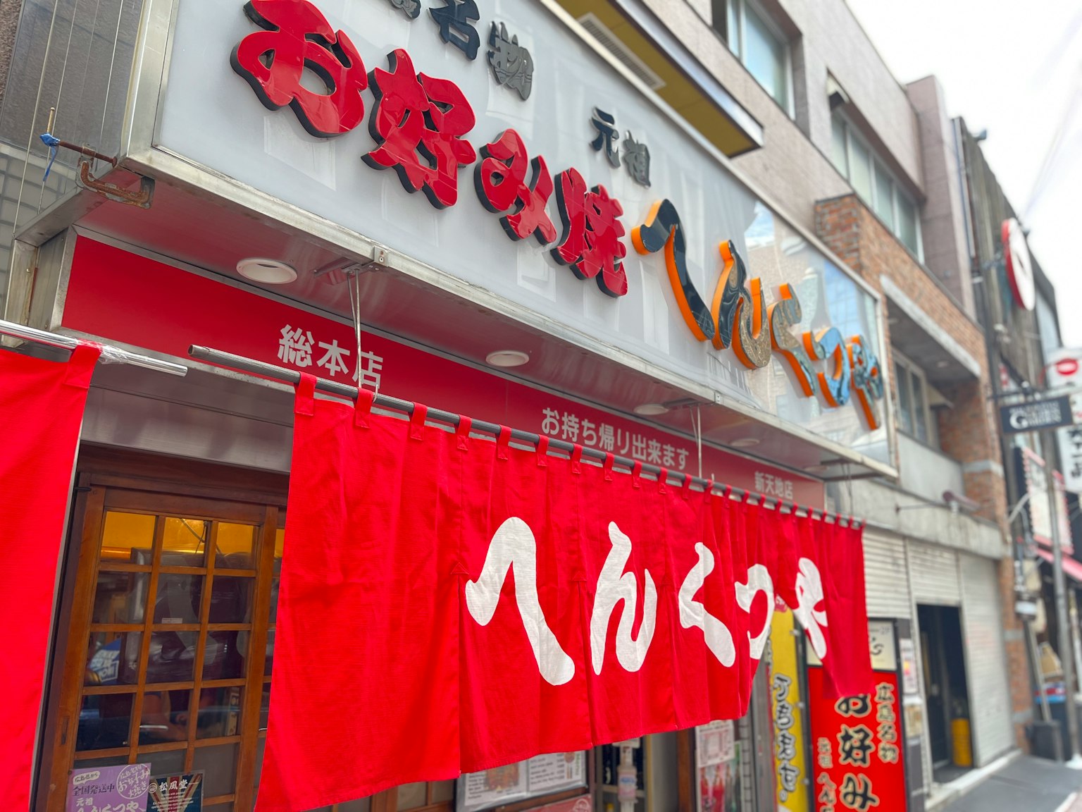 Eksterior restoran Jepang dengan spanduk merah dan nama yang mencolok