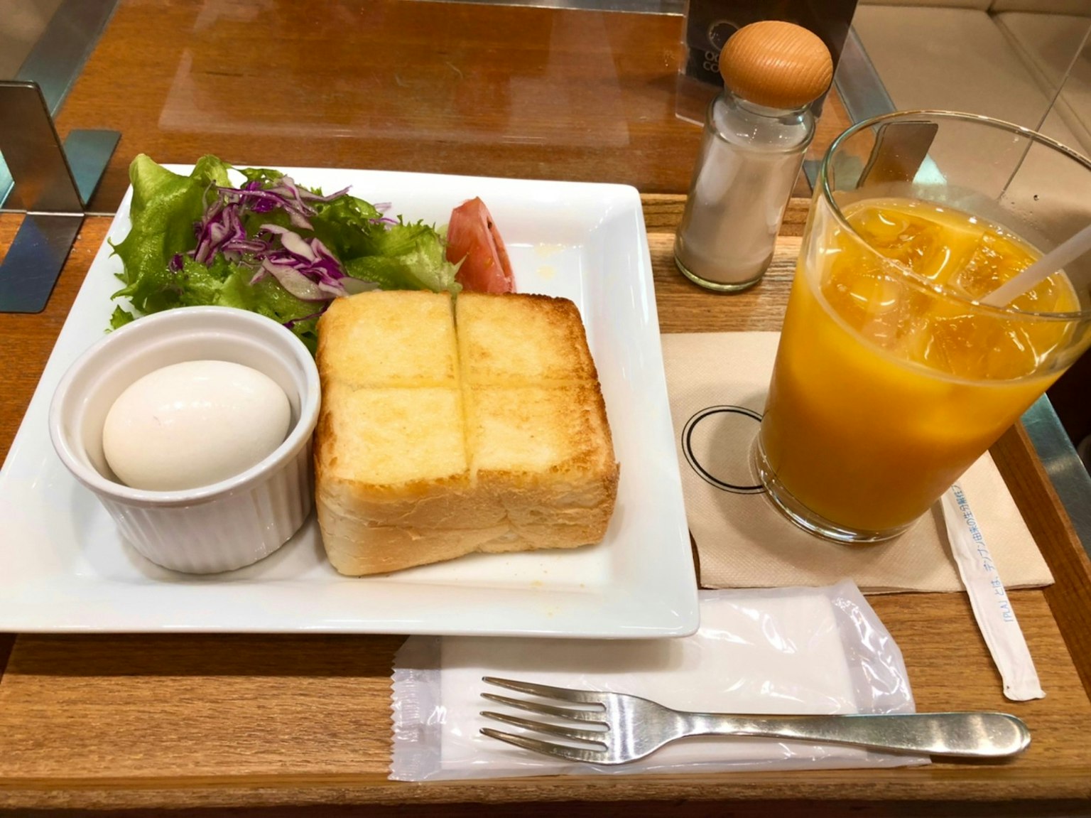 Plato de desayuno con tostada ensalada huevo cocido y jugo de naranja