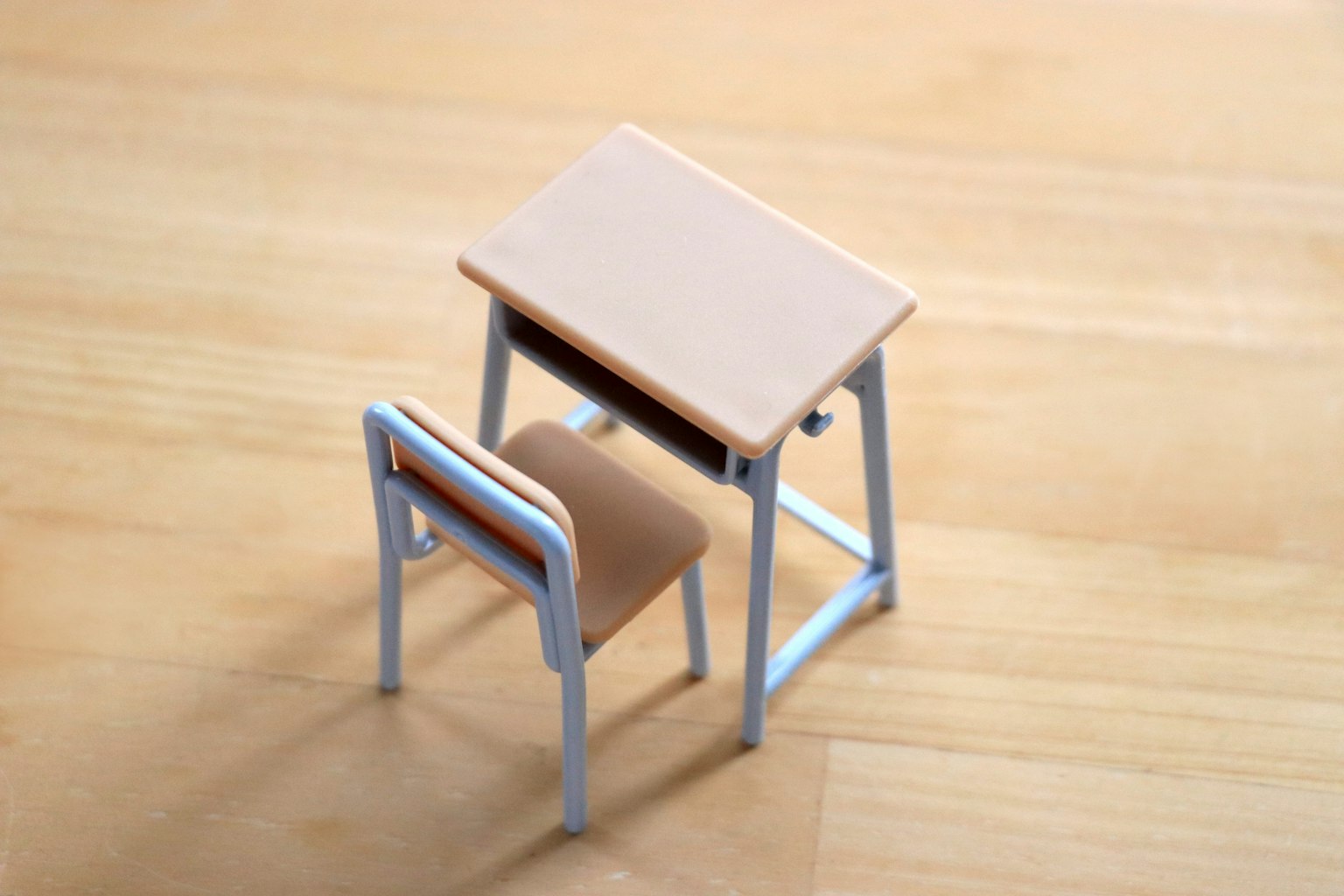 Un modèle miniature de bureau et de chaise placé sur un sol en bois