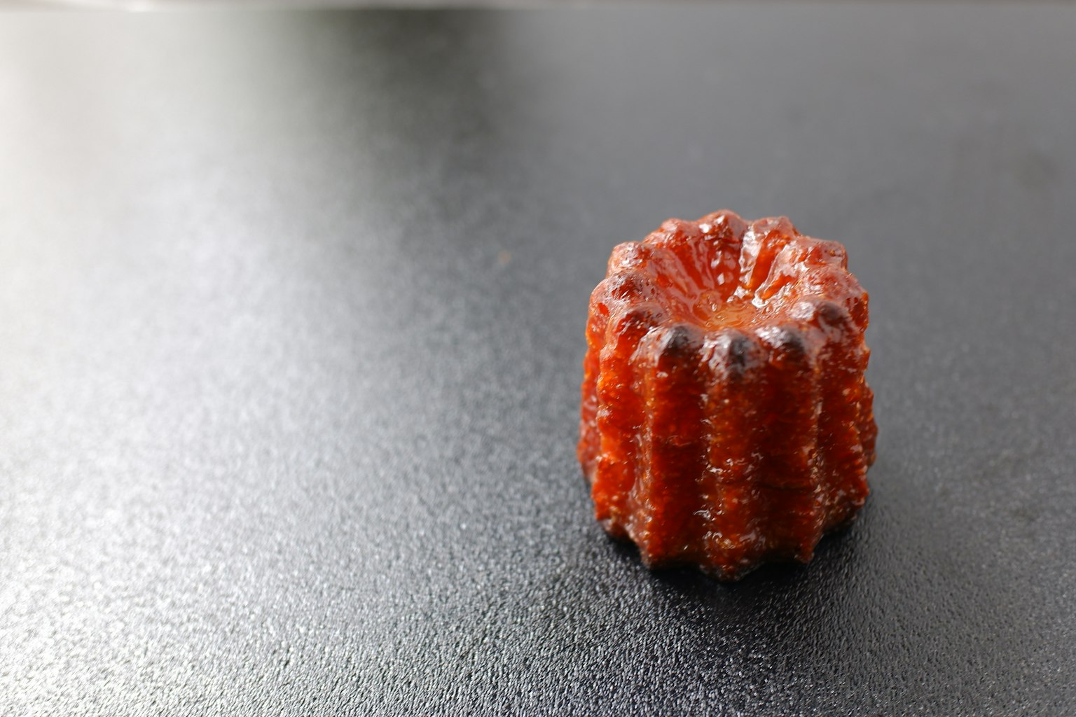 Un gâteau canelé rouge placé sur une surface noire