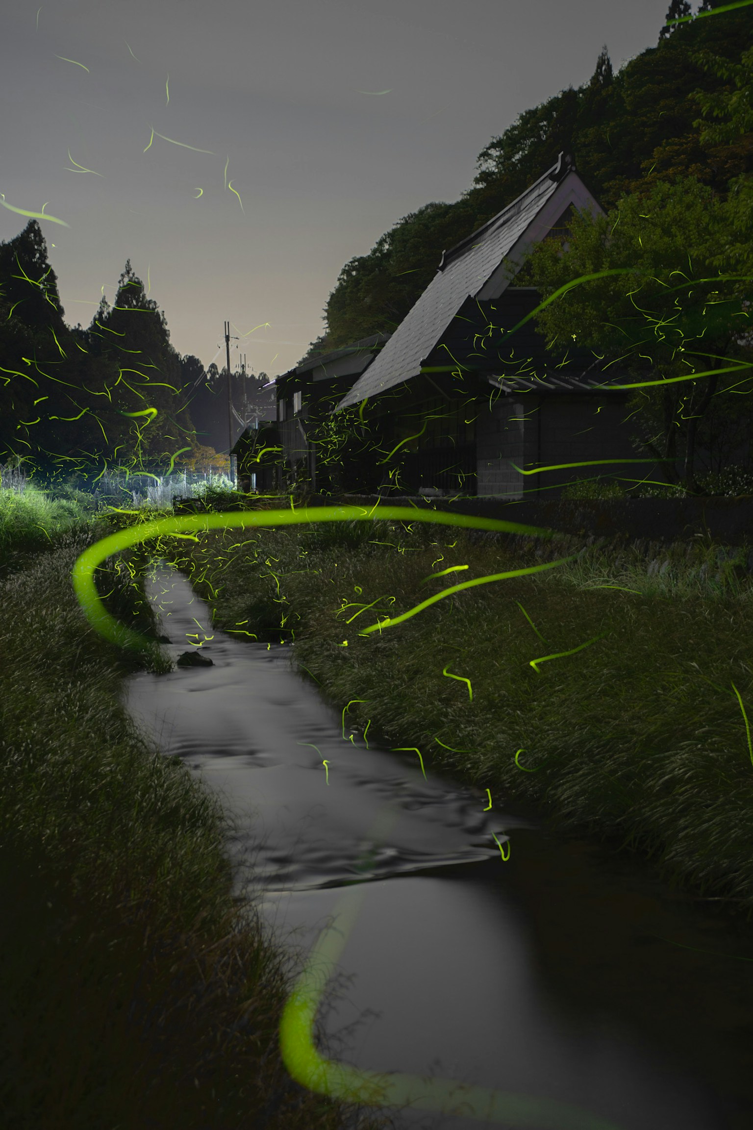 Una scena notturna magica di lucciole che illuminano un ruscello accanto a una casa di campagna