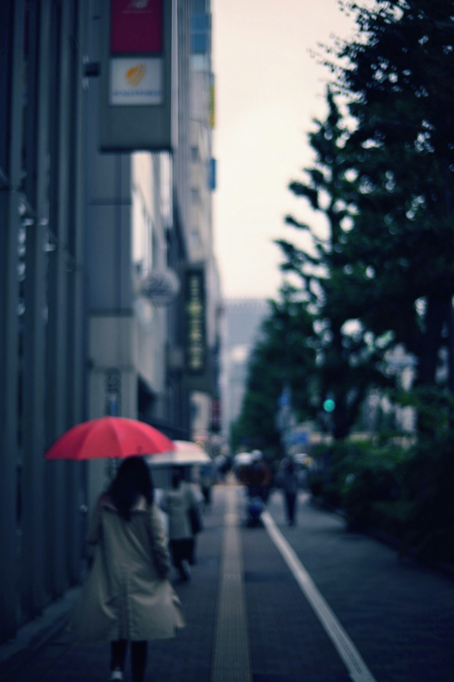 Femme marchant avec un parapluie rouge dans un cadre urbain