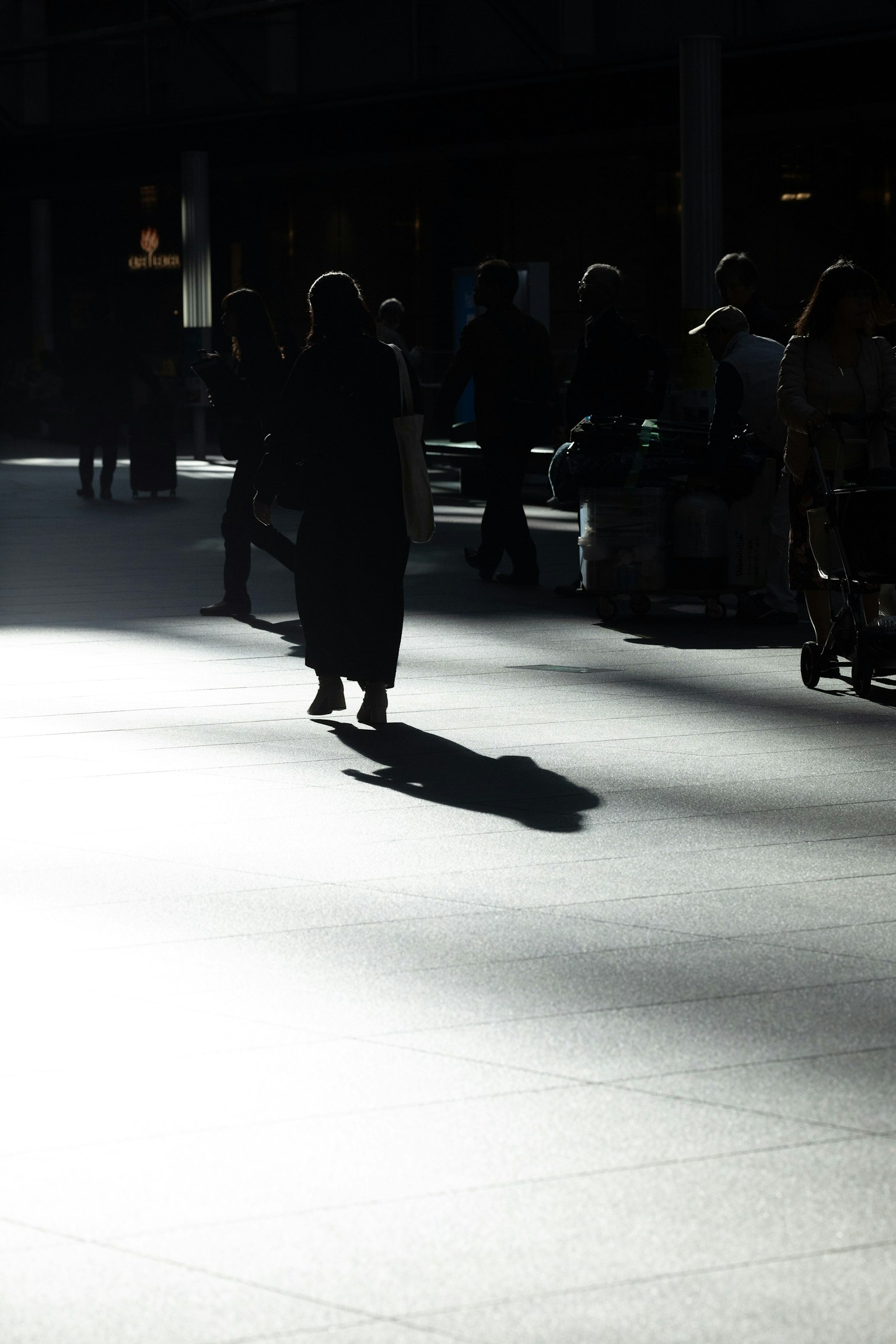 Silhouettes of people walking in shadows Bright floor contrasting with dark background