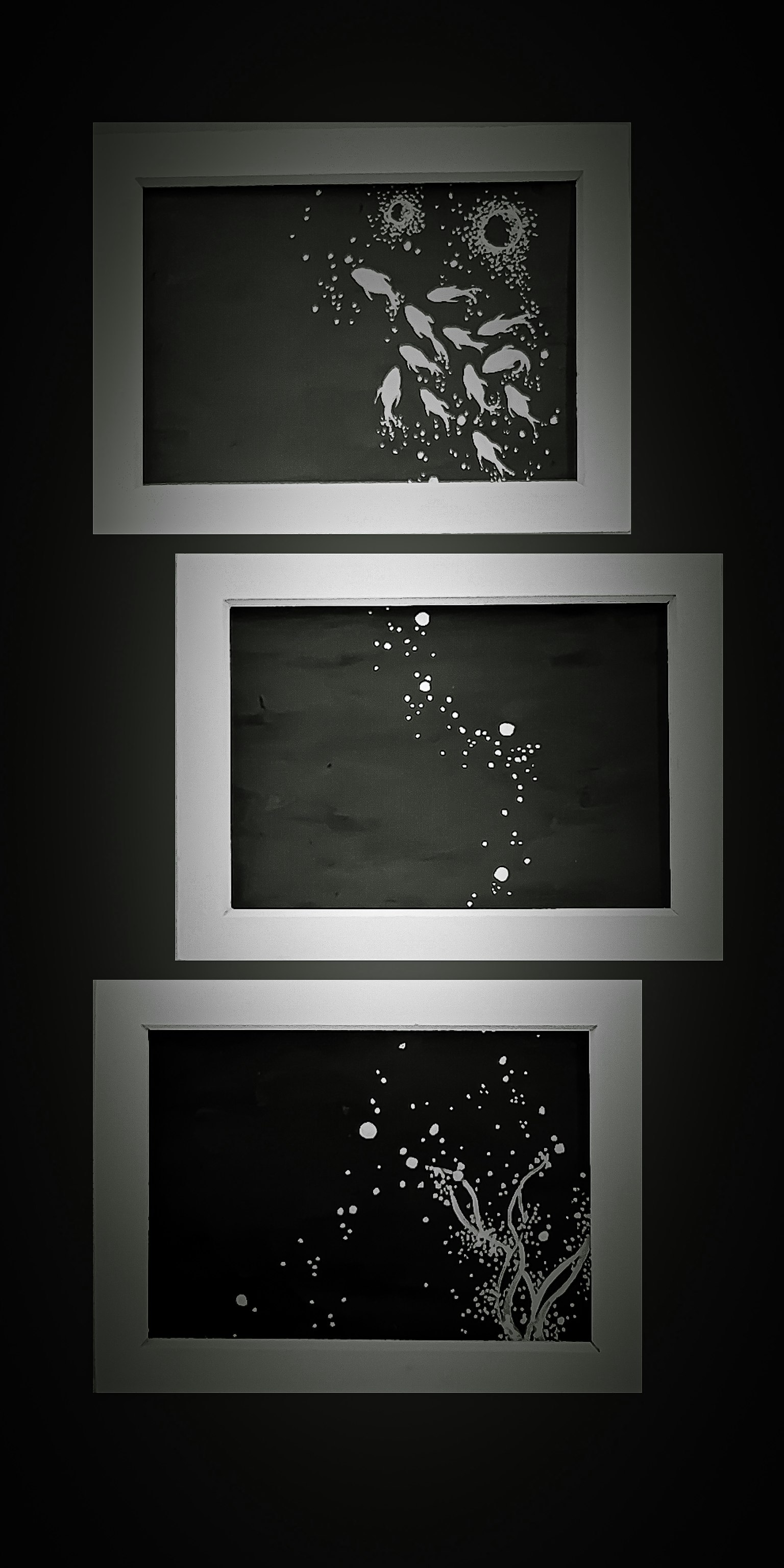 Trois œuvres encadrées avec des motifs floraux blancs sur fond noir