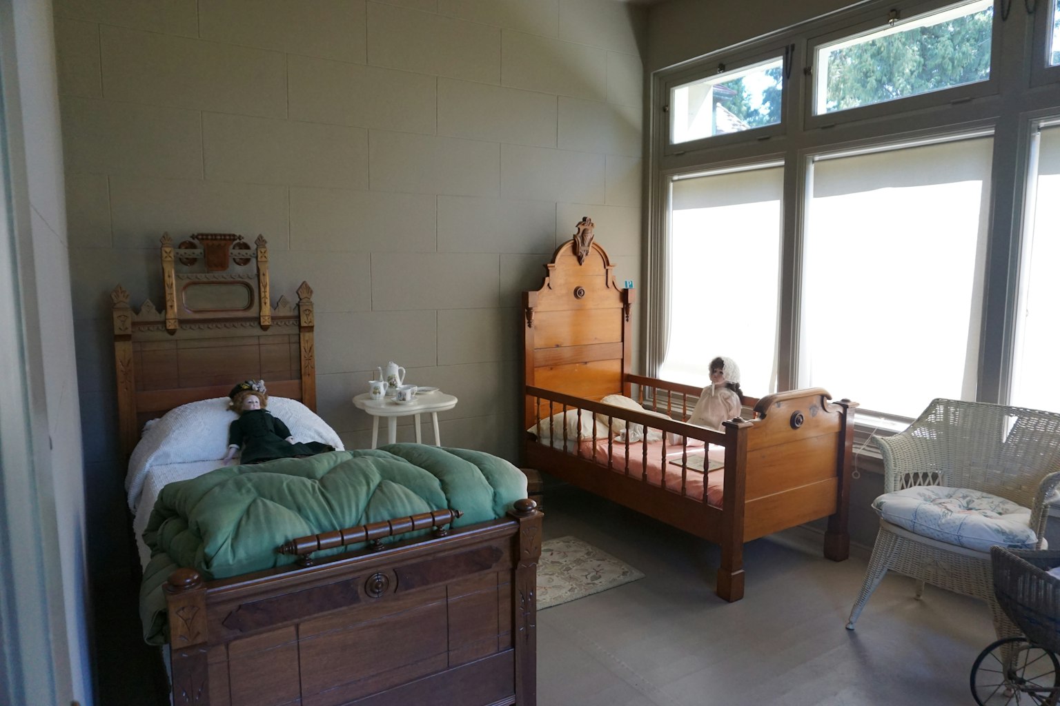 Sebuah ruangan cerah dengan dua tempat tidur kayu dan cahaya alami yang masuk melalui jendela besar