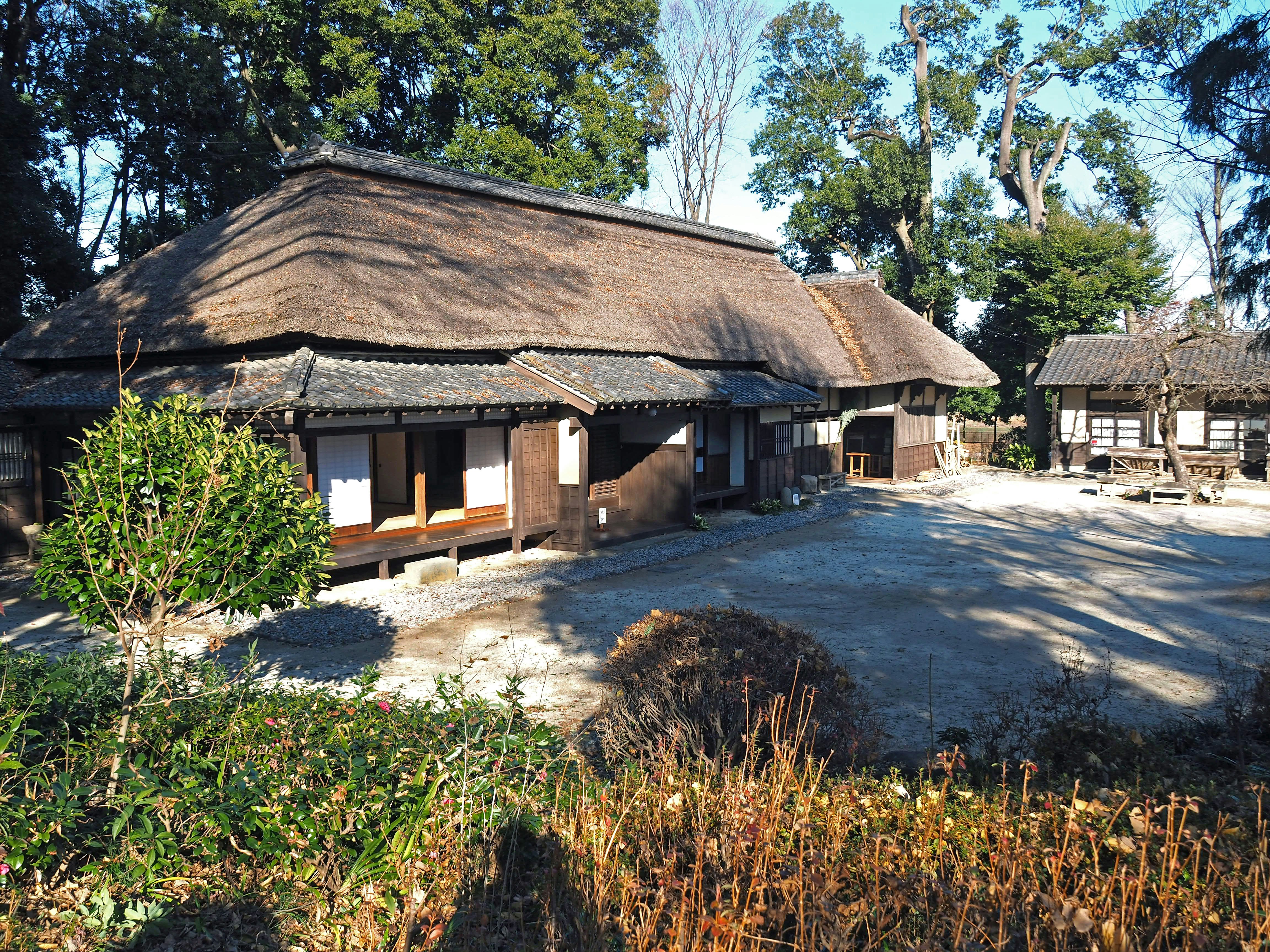 pemandangan luar dengan rumah Jepang beratap jerami dan taman
