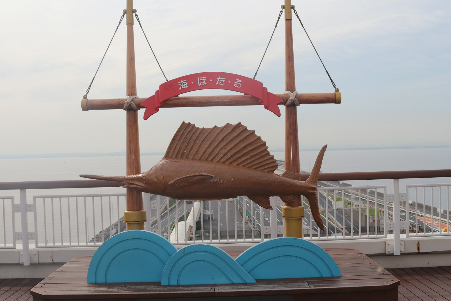海邊的木製馬林魚雕塑和藍色波浪底座