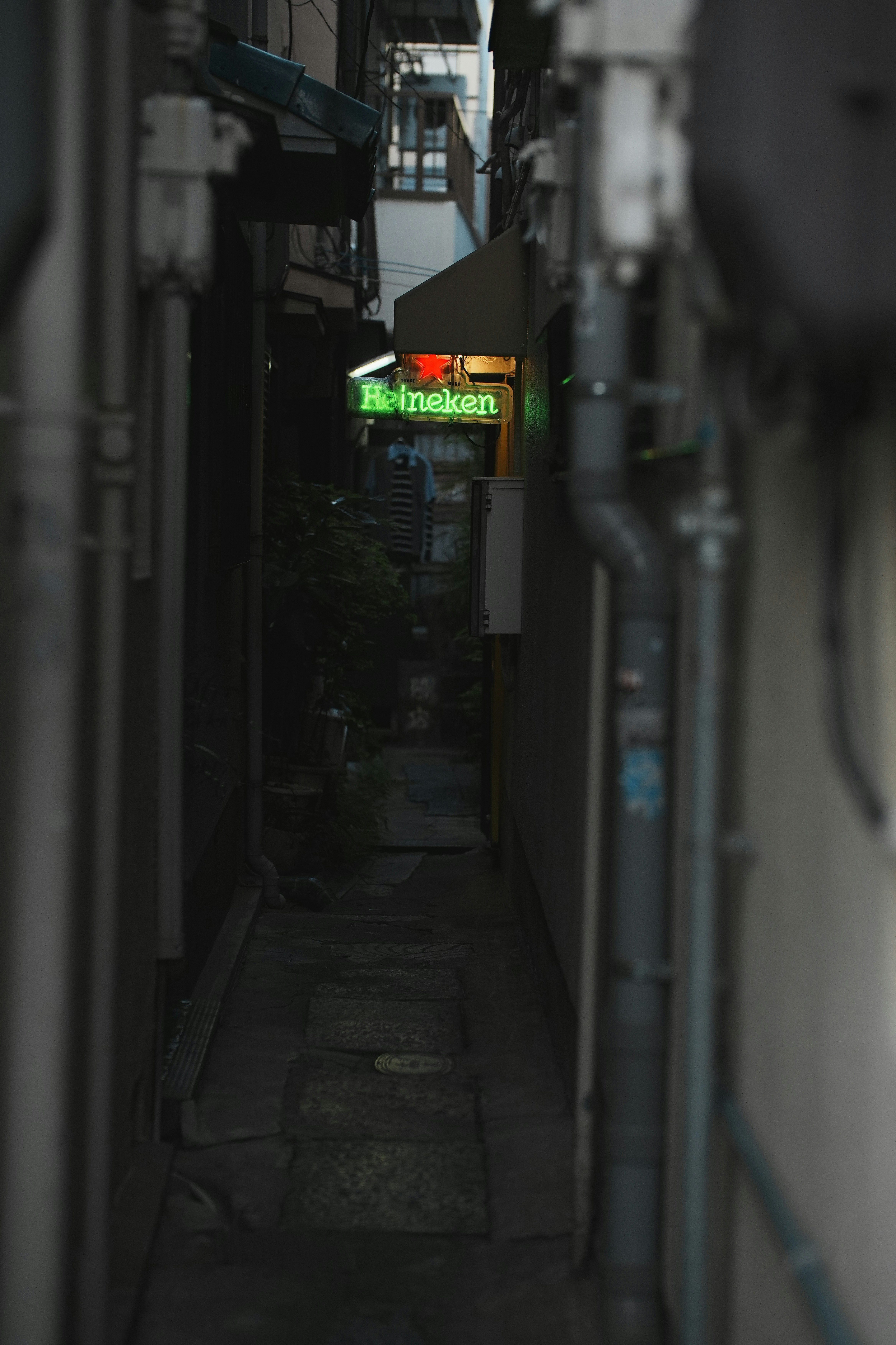 路地の奥に見えるビールの看板と配管
