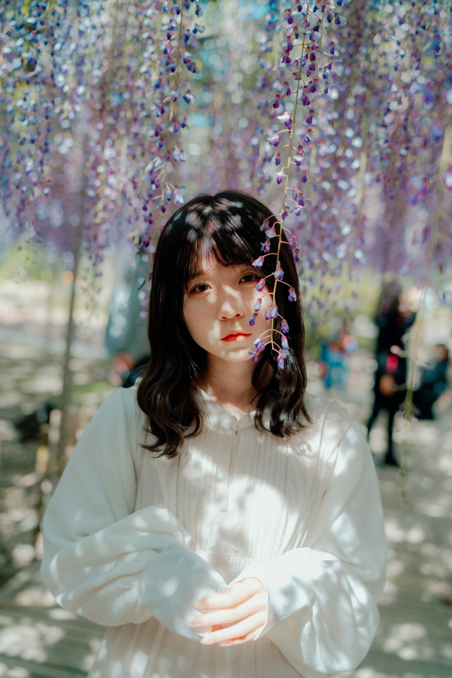 Portrait d'une femme se tenant sous des fleurs violettes