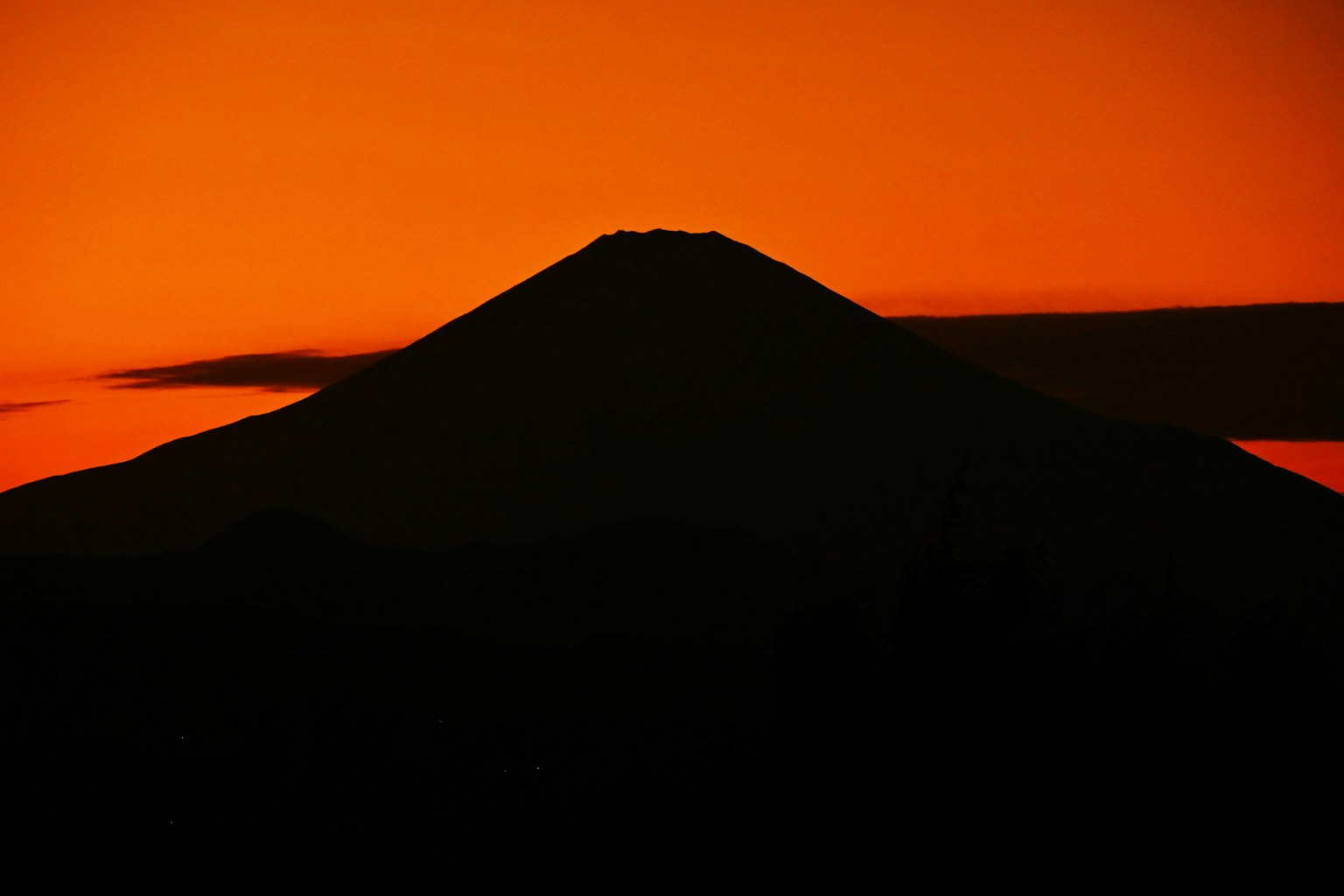 Bergsilhouette vor einem lebhaften orangefarbenen Sonnenuntergang