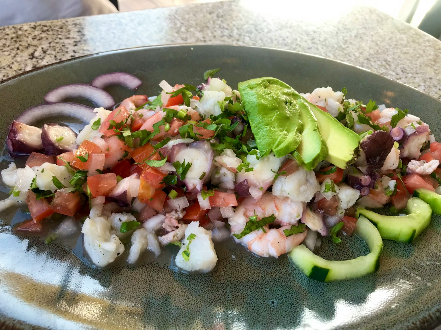Frischer Fisch-Ceviche serviert mit Tomaten, Zwiebeln und Avocado auf einem Teller