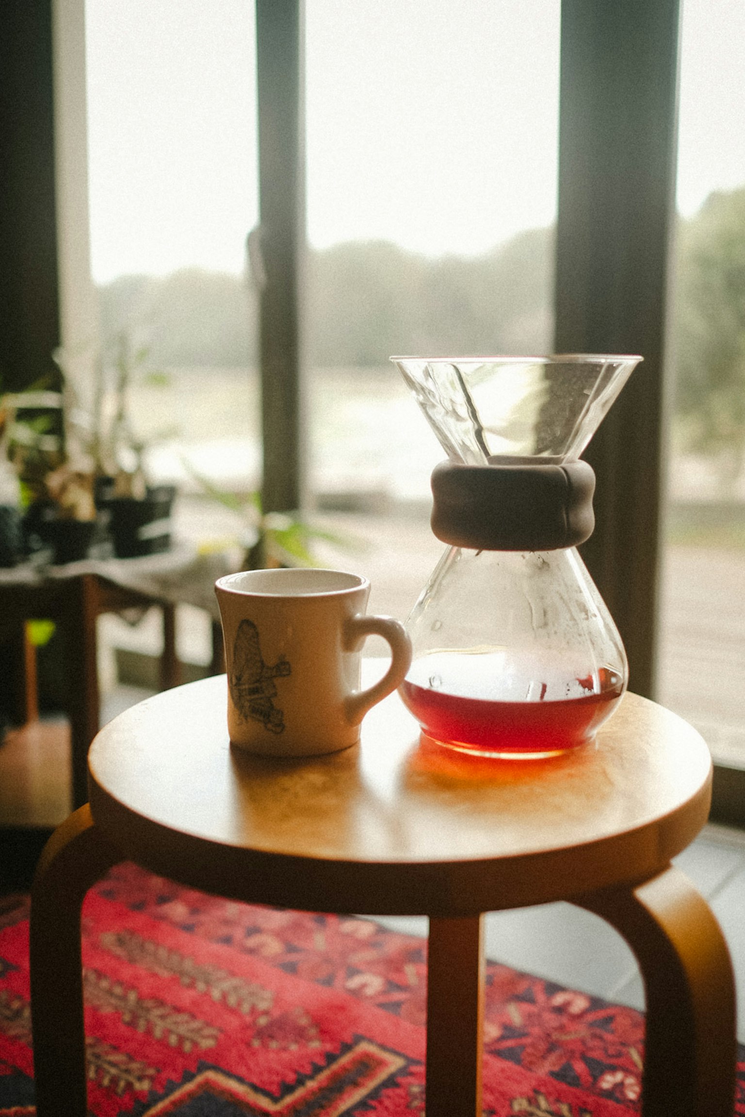 ฉากที่มีเครื่องชงกาแฟและถ้วยบนโต๊ะไม้พร้อมเครื่องดื่มอุ่น