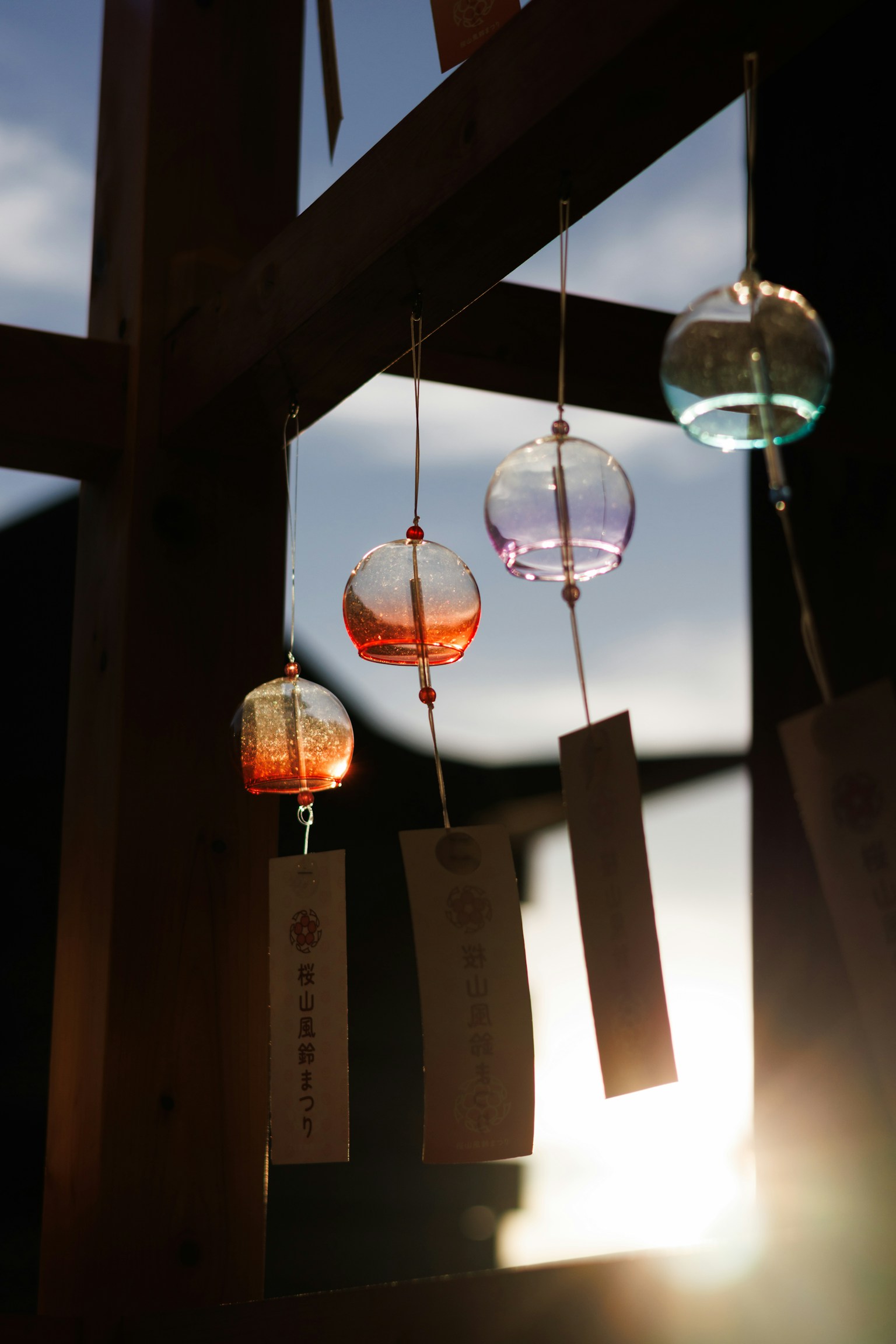 色彩繽紛的風鈴懸掛在木結構上，夕陽西下