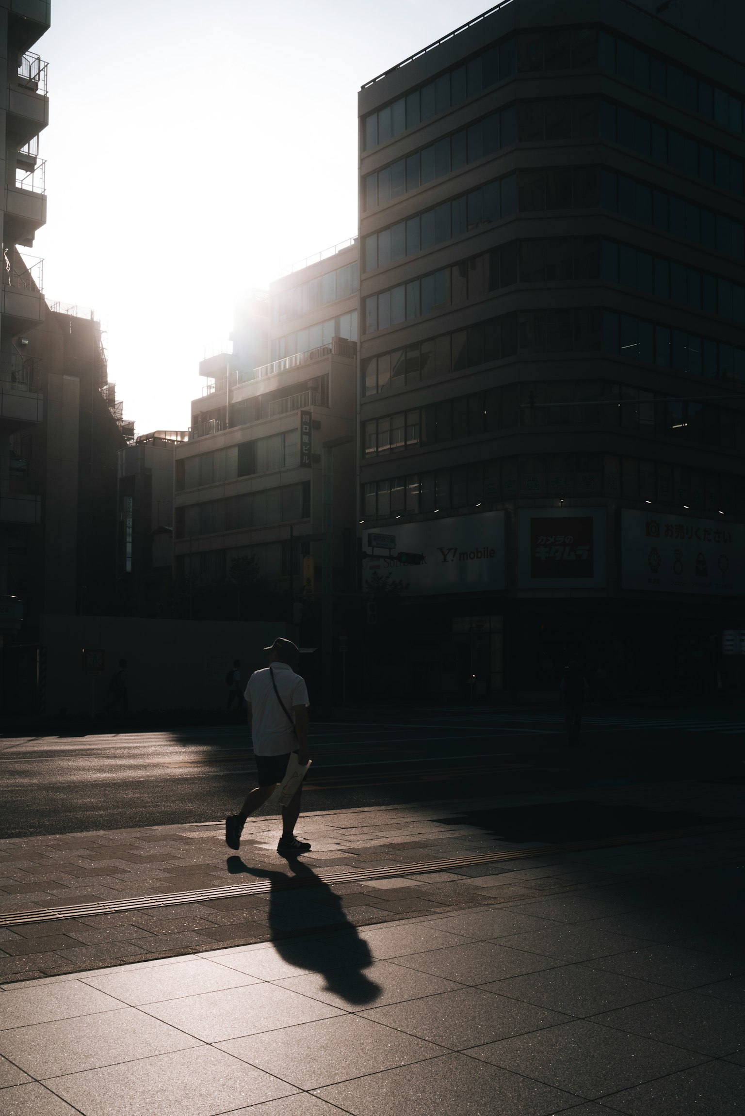 Una silueta de una persona caminando en un paisaje urbano con luz solar brillante