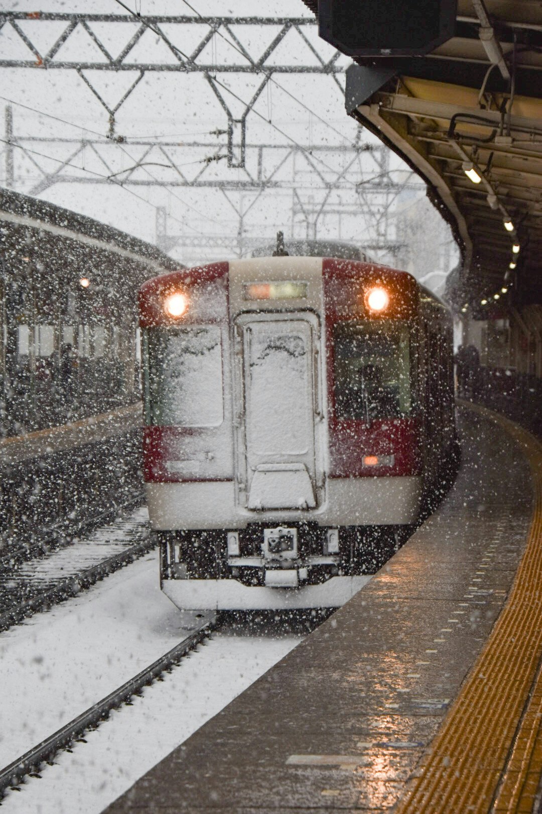 雪の降る駅ホームで停車する電車の前面