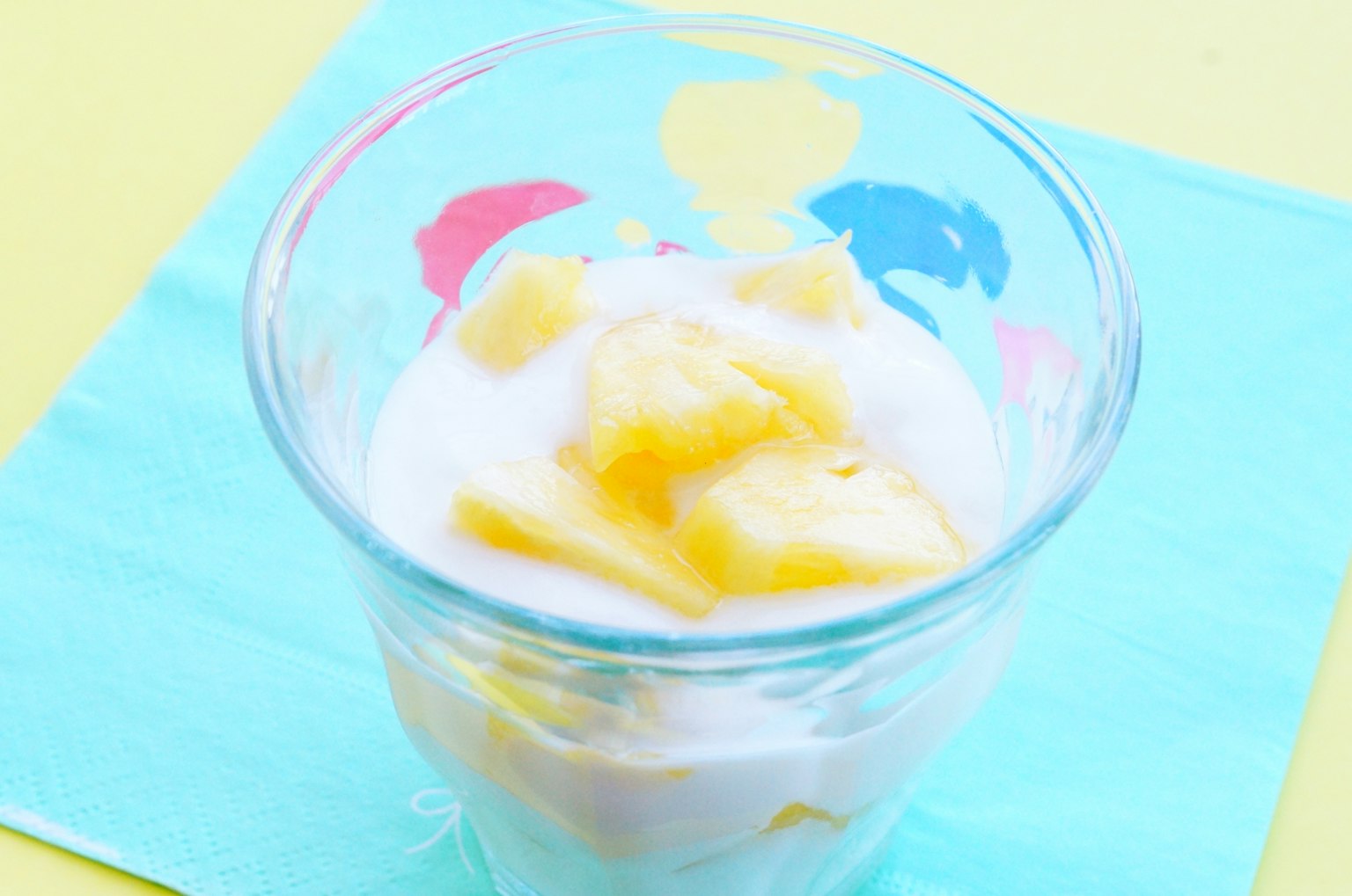 Yogurt dessert topped with fresh mango in a colorful glass