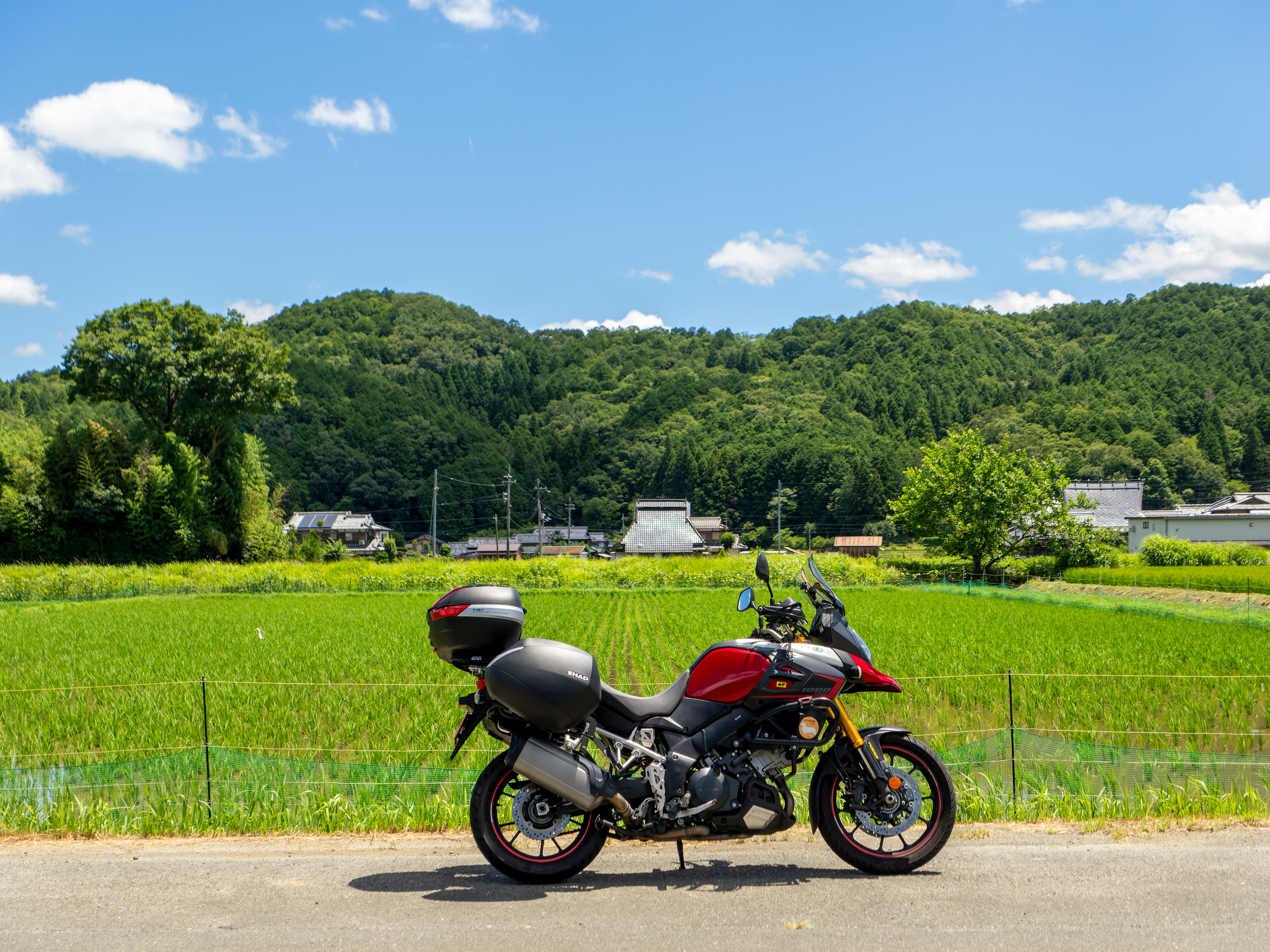 夏のツーリングで草原の道に停めたバイク