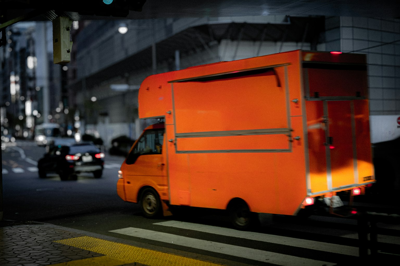 Camión de entrega naranja en la calle de la ciudad por la noche