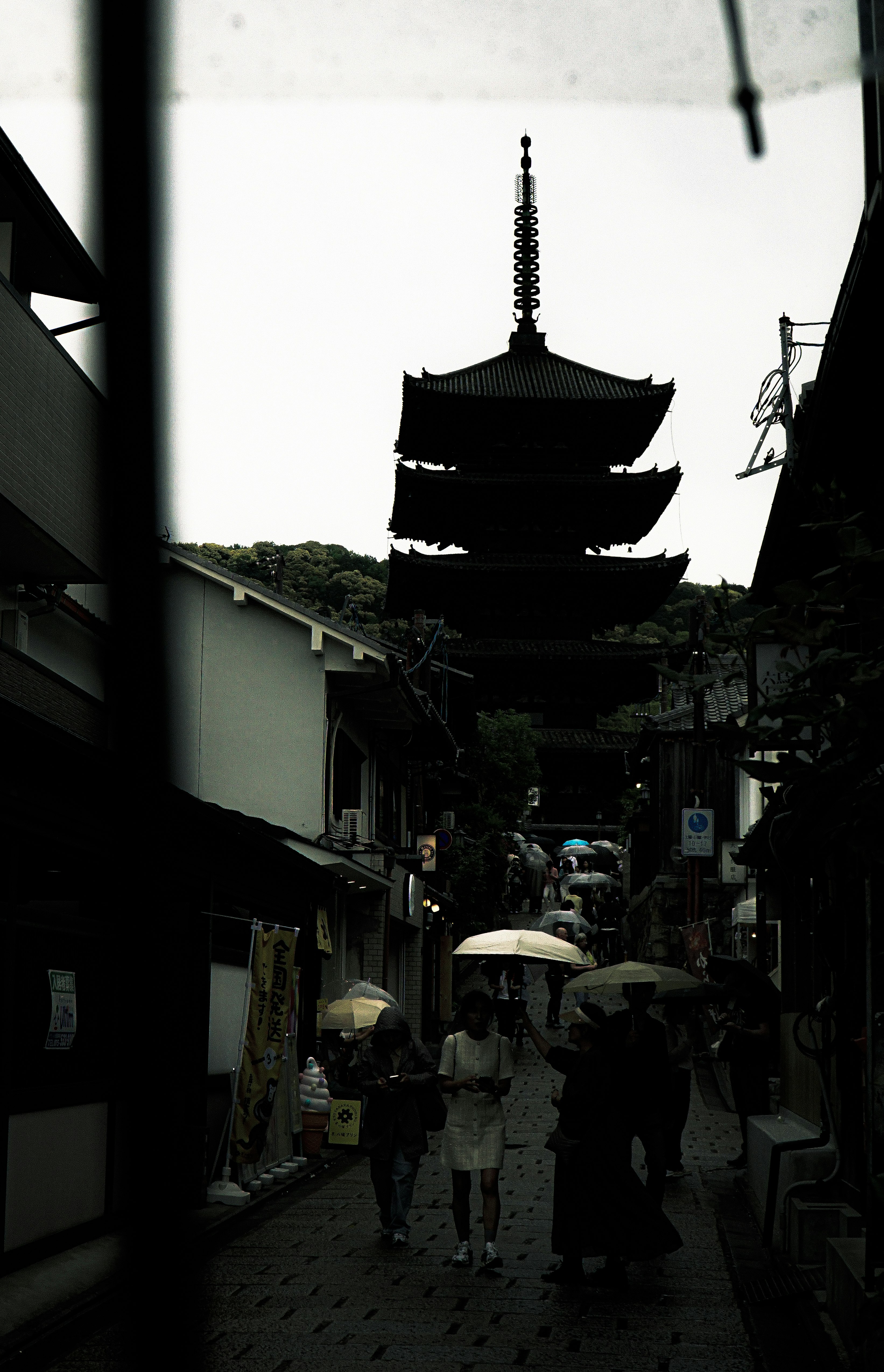 路地の奥にそびえる寺院の五重塔と人々の往来