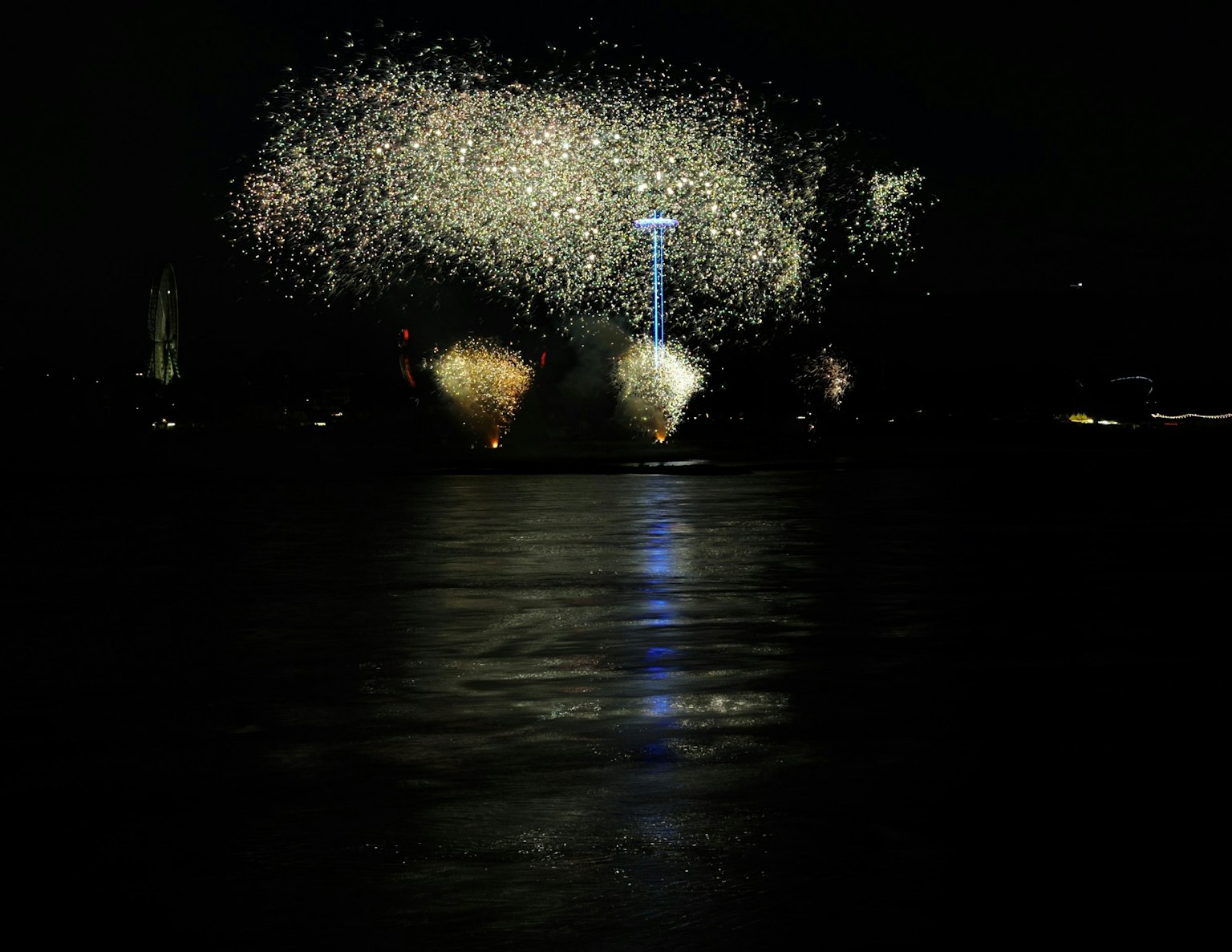 Feuerwerk erhellt den Nachthimmel mit Reflexionen auf dem Wasser