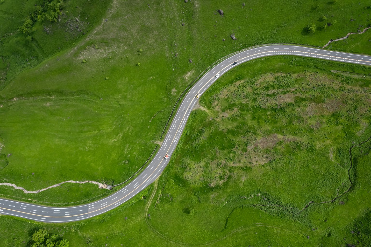 Aerial view of a winding road through lush green fields