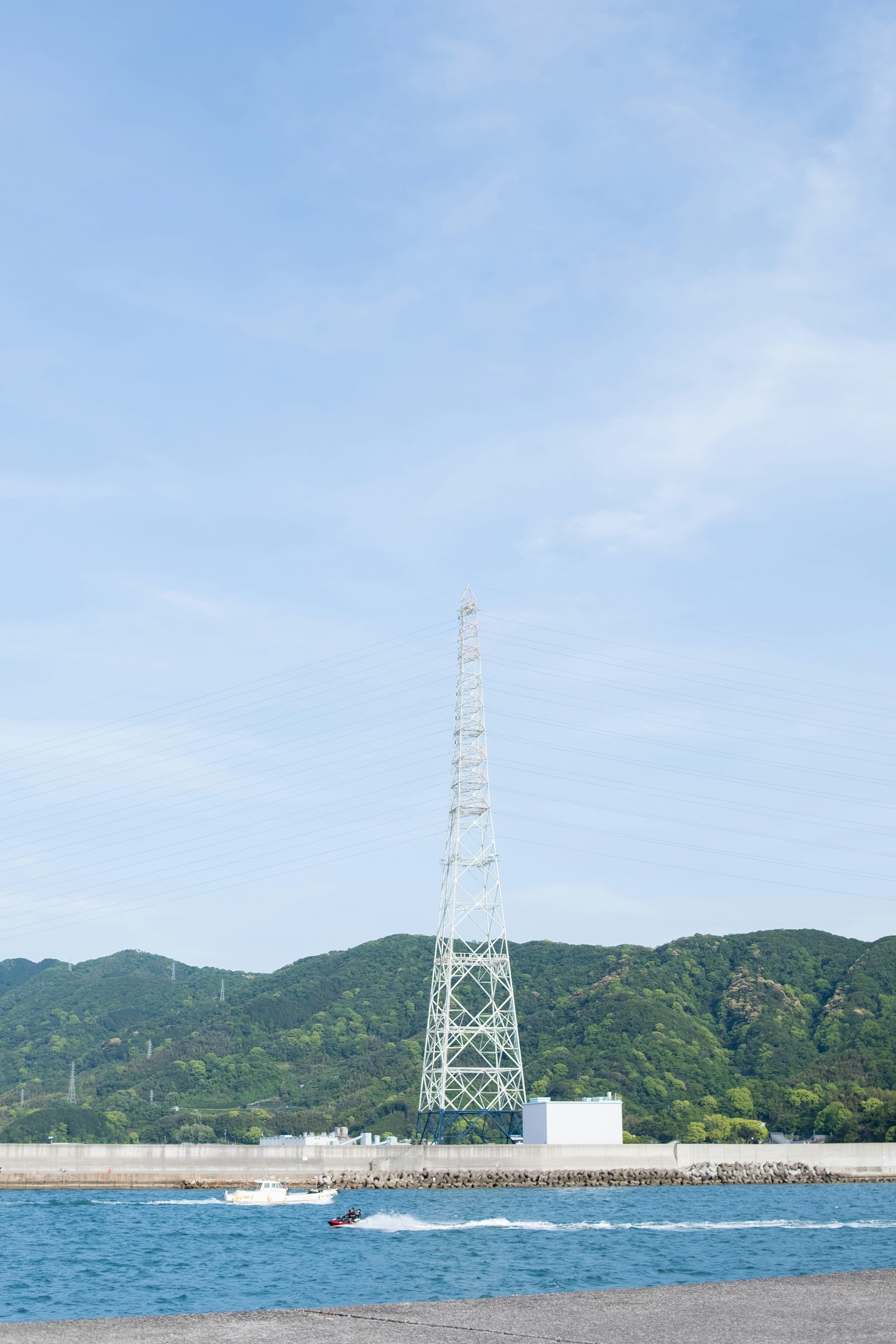 海辺の防波堤と送電鉄塔のある風景