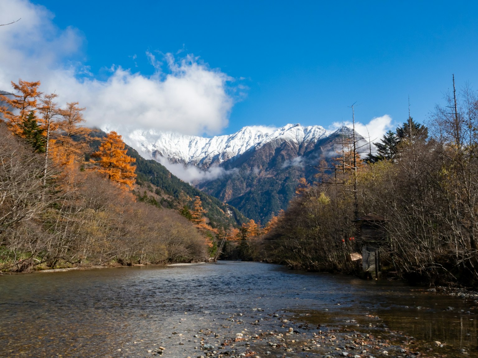 Malersches Flusslandschaft mit Herbstlaub und schneebedeckten Bergen