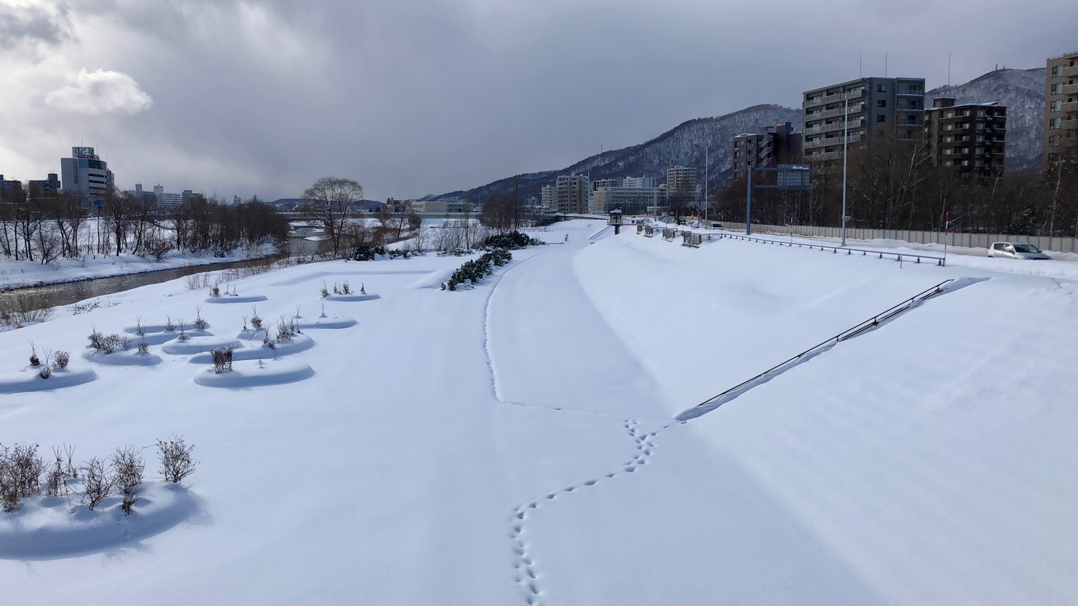 Schneebedeckte Flusslandschaft mit umliegenden Gebäuden