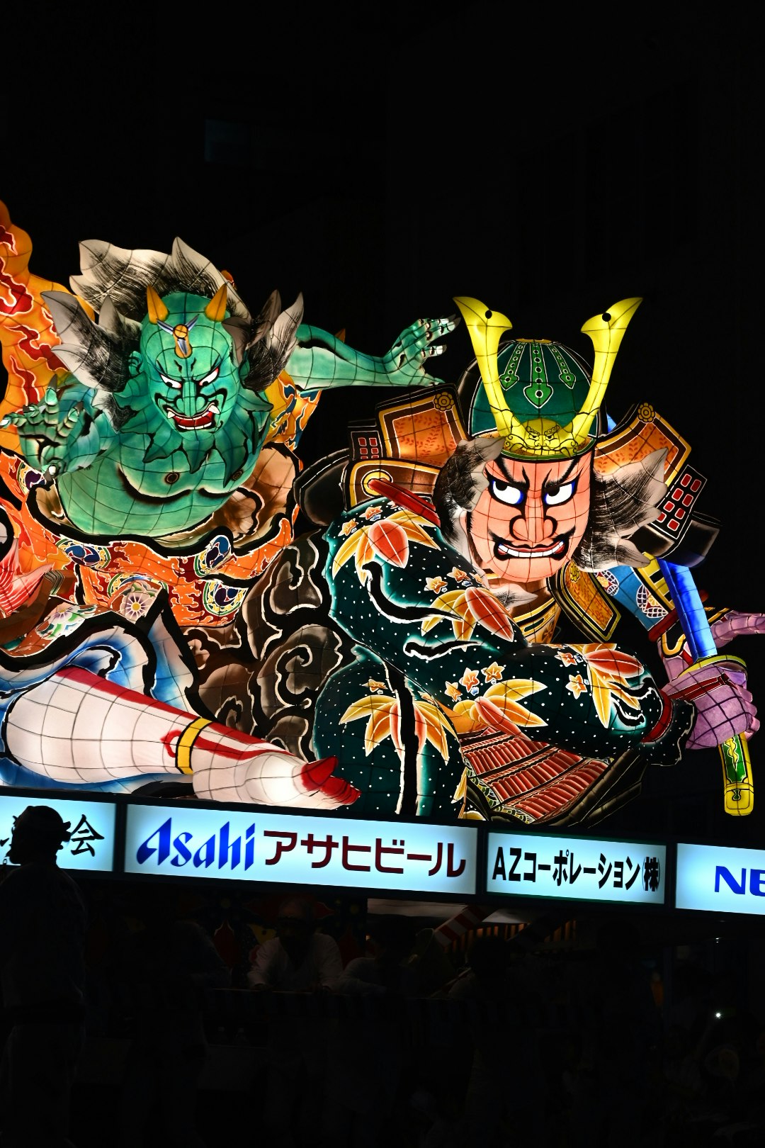 緑の鬼面と武者の兜を並べた祭りの飾りの看板