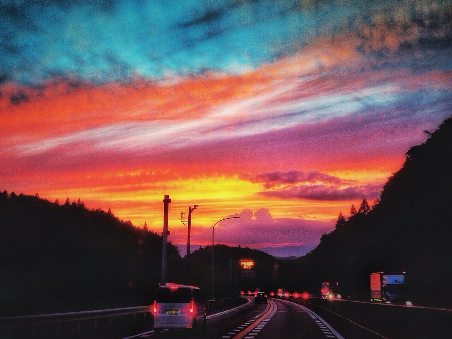 壮观的日落场景，前景有一条道路，天空呈现出鲜艳的橙色和紫色