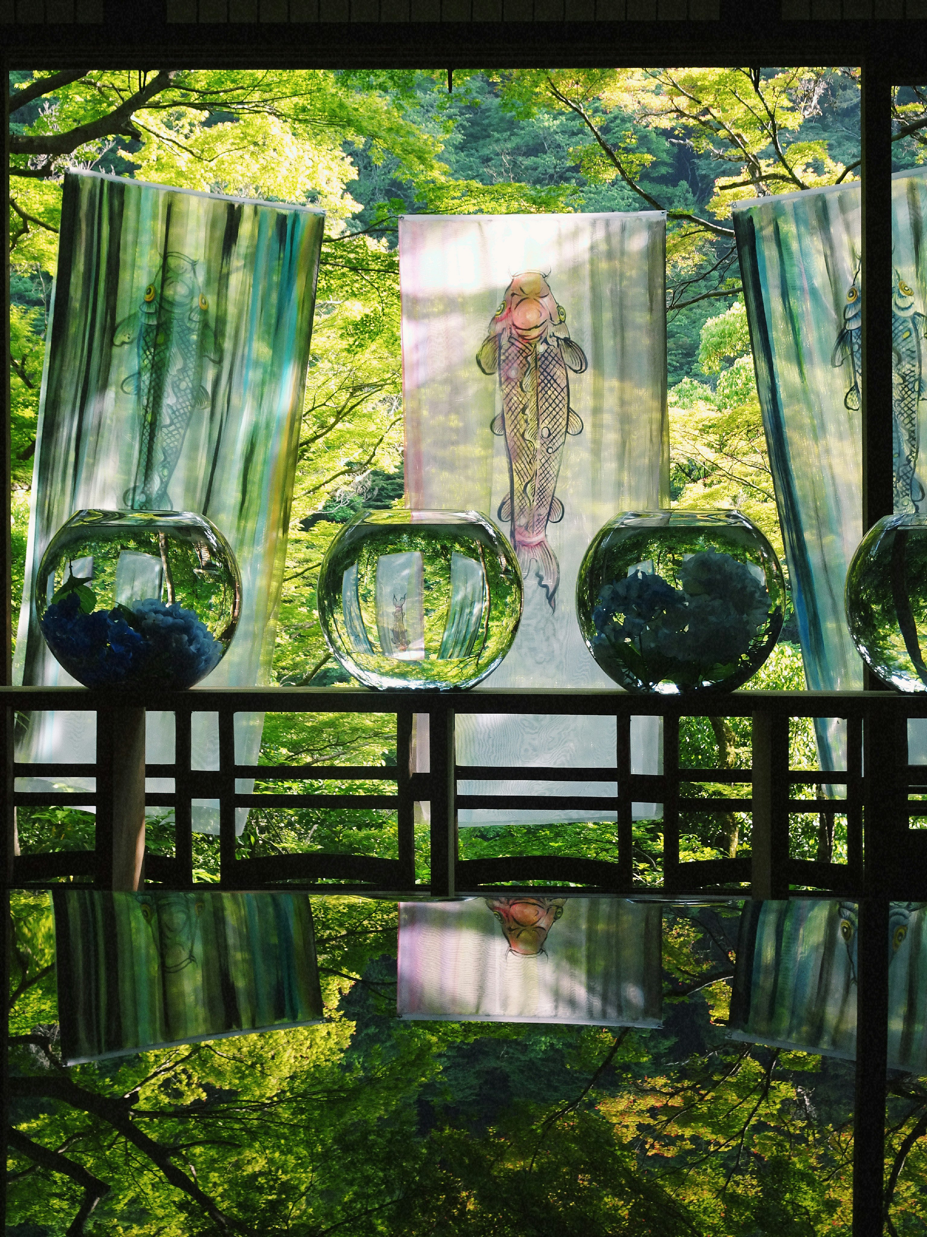 緑の森を背景にしたガラスの花器と花の装飾