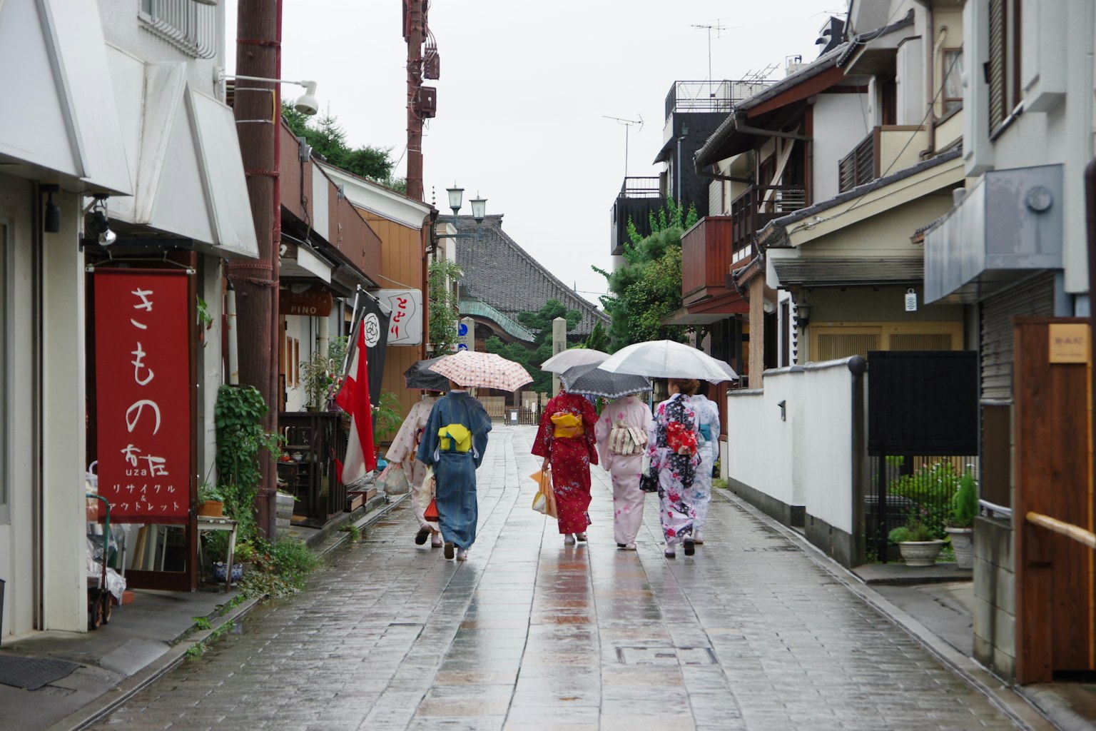 Women in traditional kimonos walking with umbrellas in a rainy street