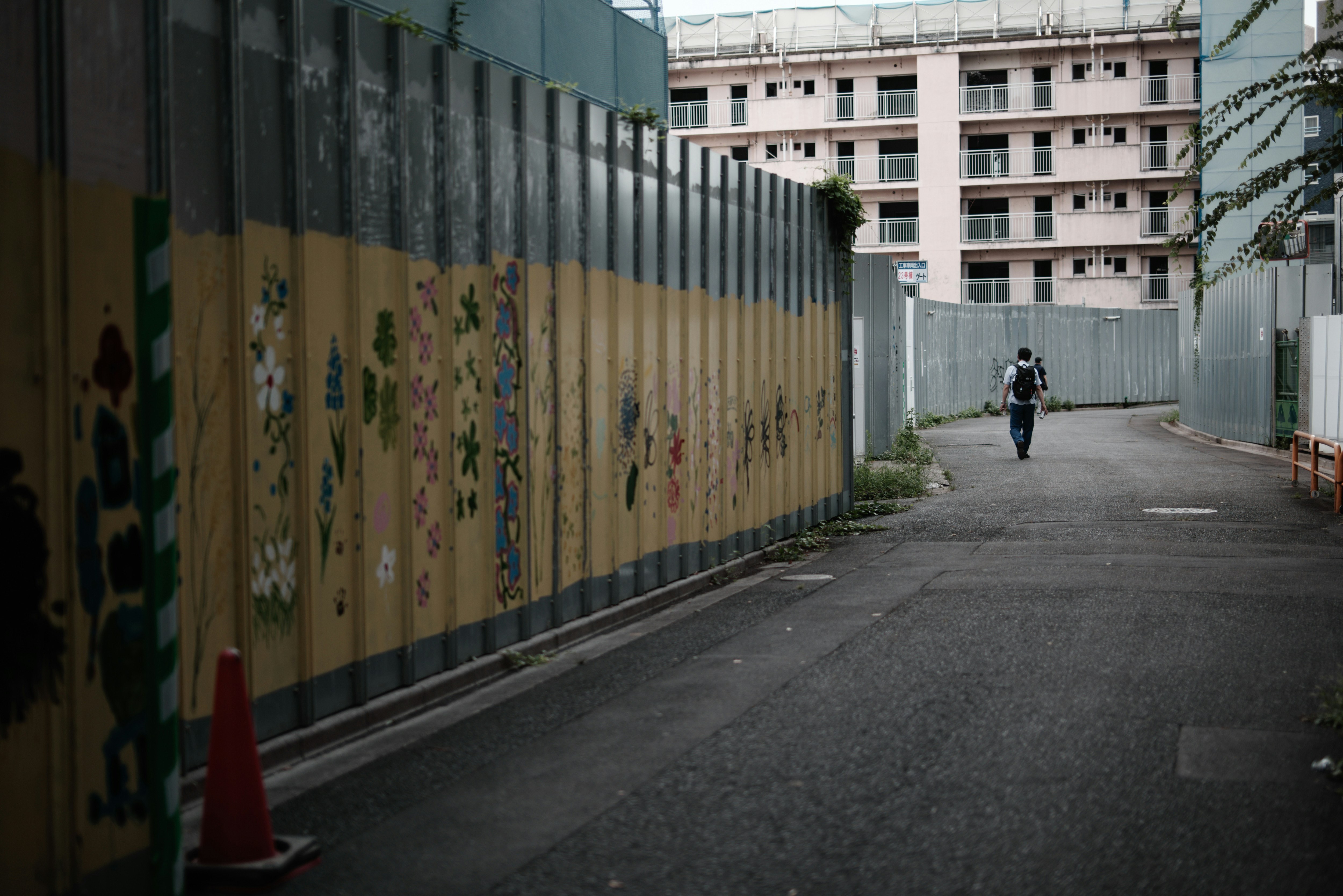 un callejón con una persona caminando junto a un sitio de demolición en el complejo de viviendas de Kita-Aoyama
