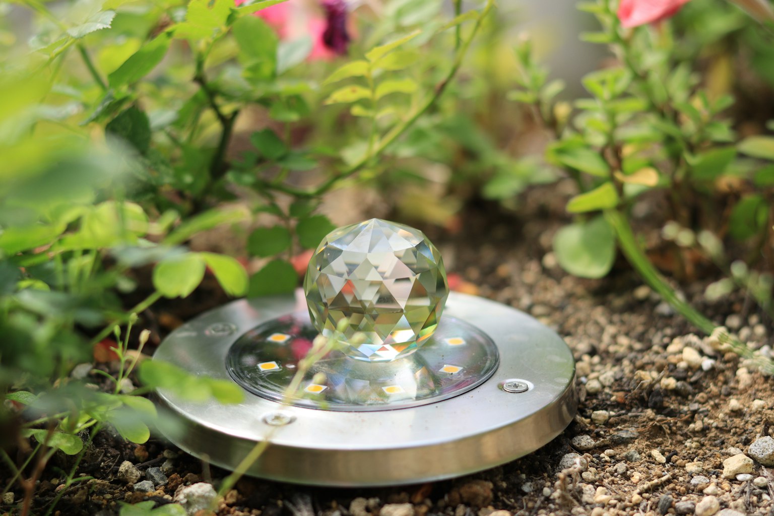 Kristallkugel auf metallischer Basis umgeben von Grün und Blumen